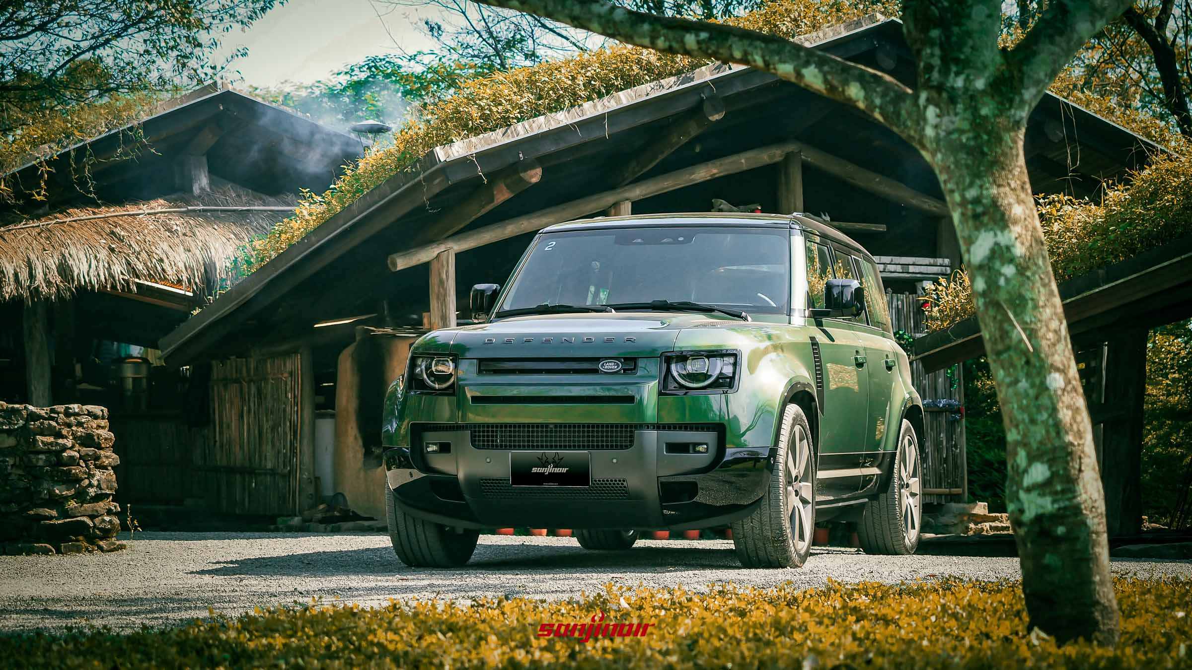 26年式綠色Defender停靠於不老部落傳統茅草屋前。
