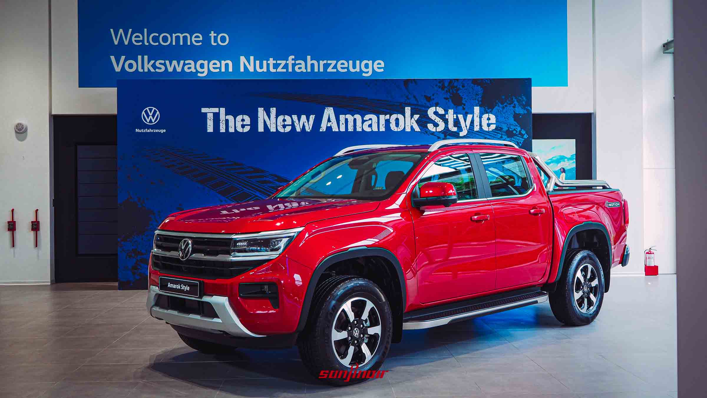 紅色Volkswagen Amarok Style停放於展間，背景為藍色品牌背板寫著「The New Amarok Style」。