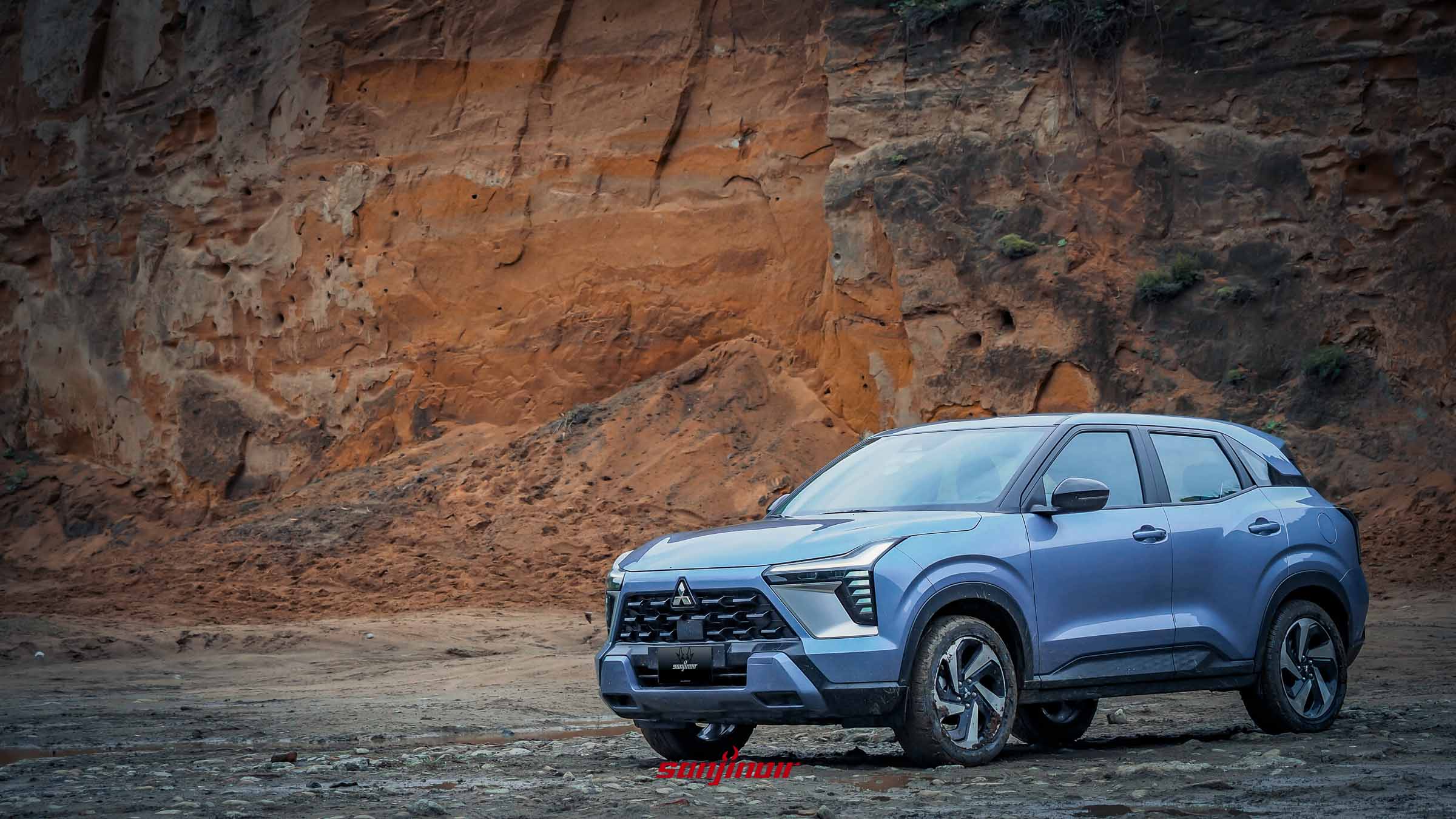 藍色Mitsubishi XForce狂享版停駐於新北水牛坑的粗獷岩壁前。