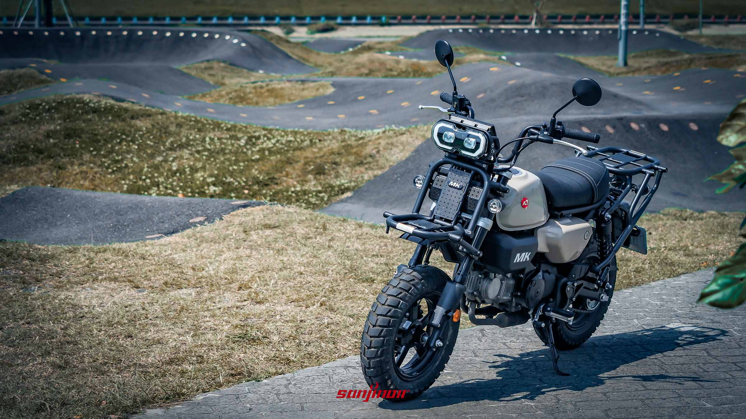 Aeontek MK150跨界輕檔車停放在都會公園中，展示獨特雙透鏡頭燈與前置物架設計。