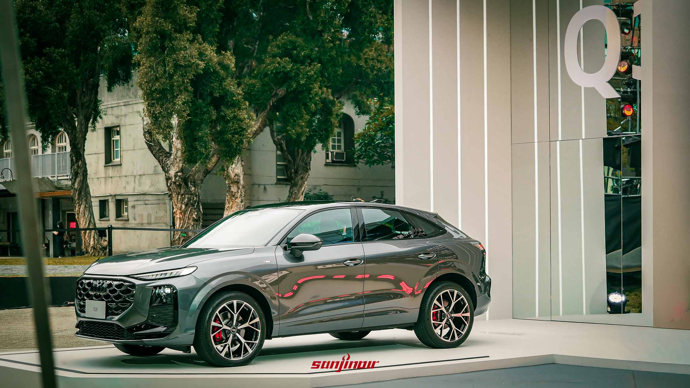 灰色AudiQ3Sportback於戶外發表會舞台側面展示流線斜背車身。