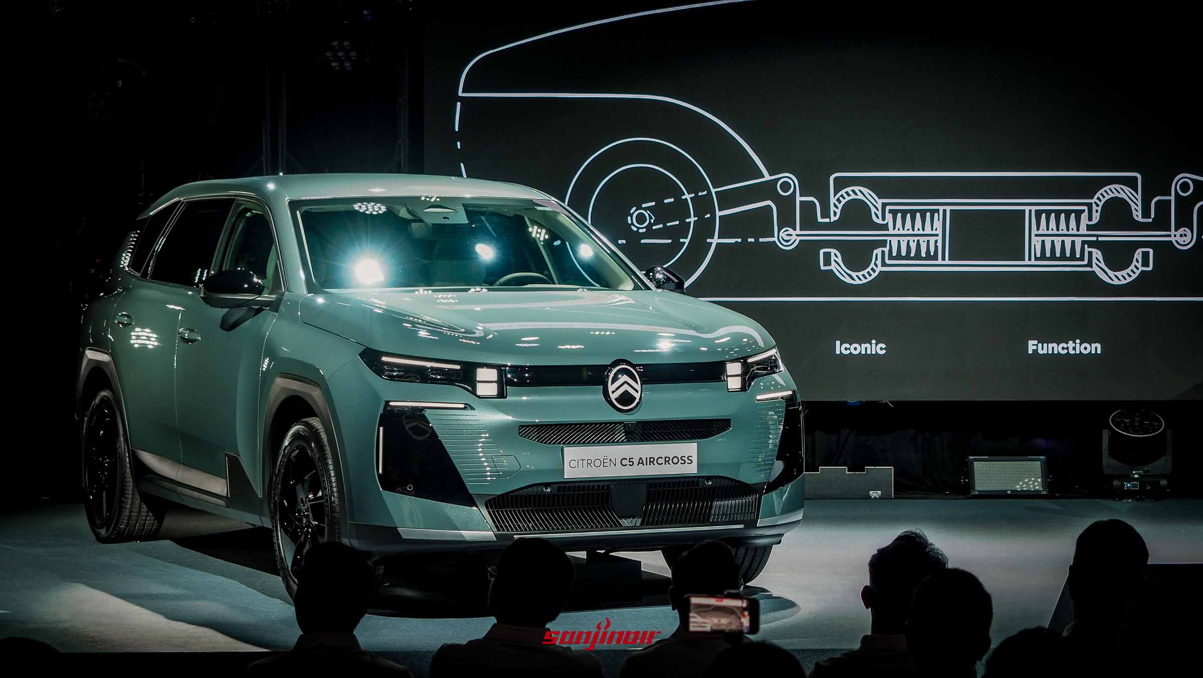 2026年CITROËN C5 Aircross發表會現場，舞台中央展示著灰綠色新車，後方大螢幕顯示懸吊系統結構圖。
