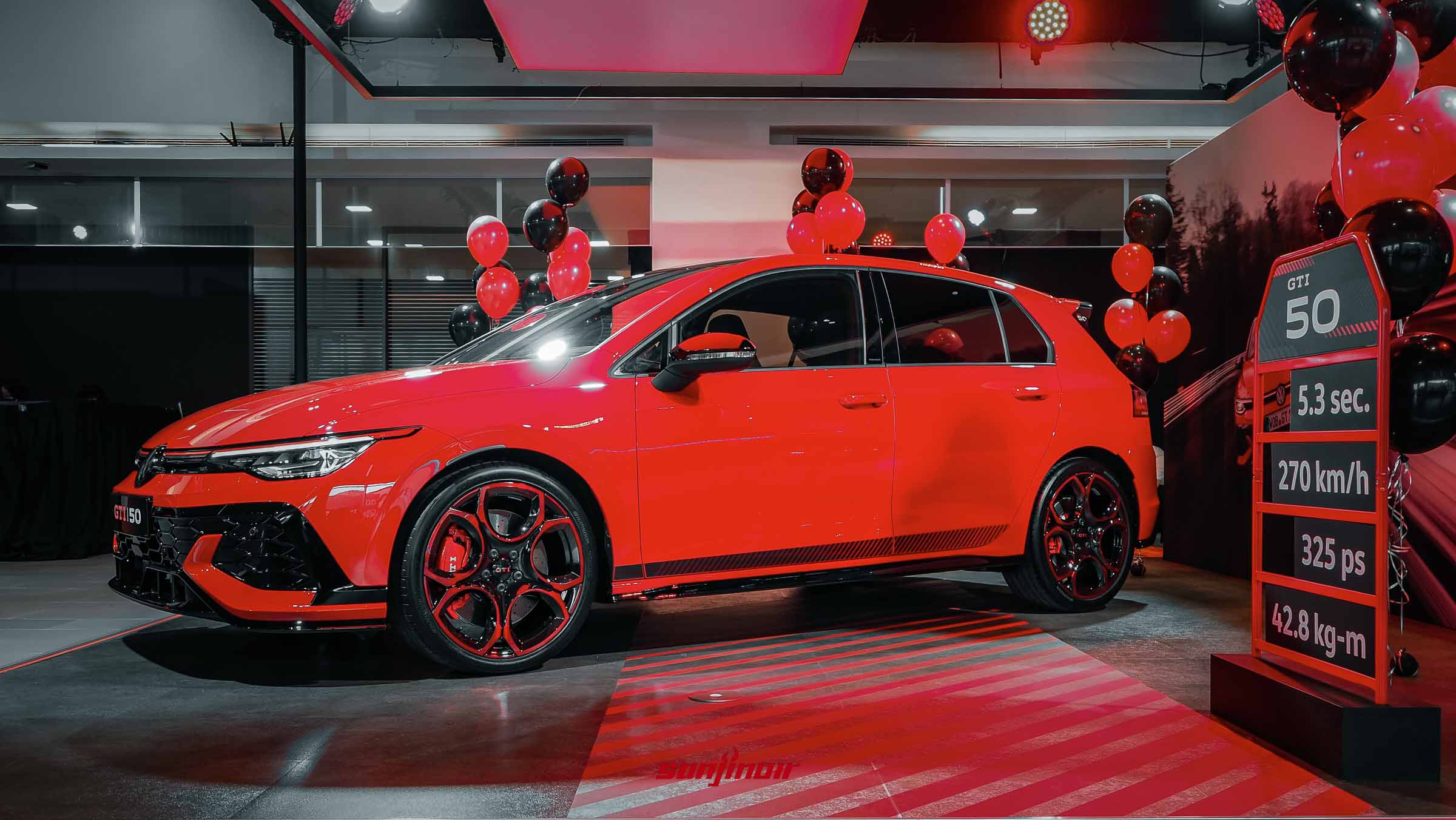 紅色Volkswagen Golf GTI EDITION 50側面照，配備高光澤黑化車頂與19吋雙色切削鋁圈，一旁設有標示5.3秒、270km/h等數據的立牌。