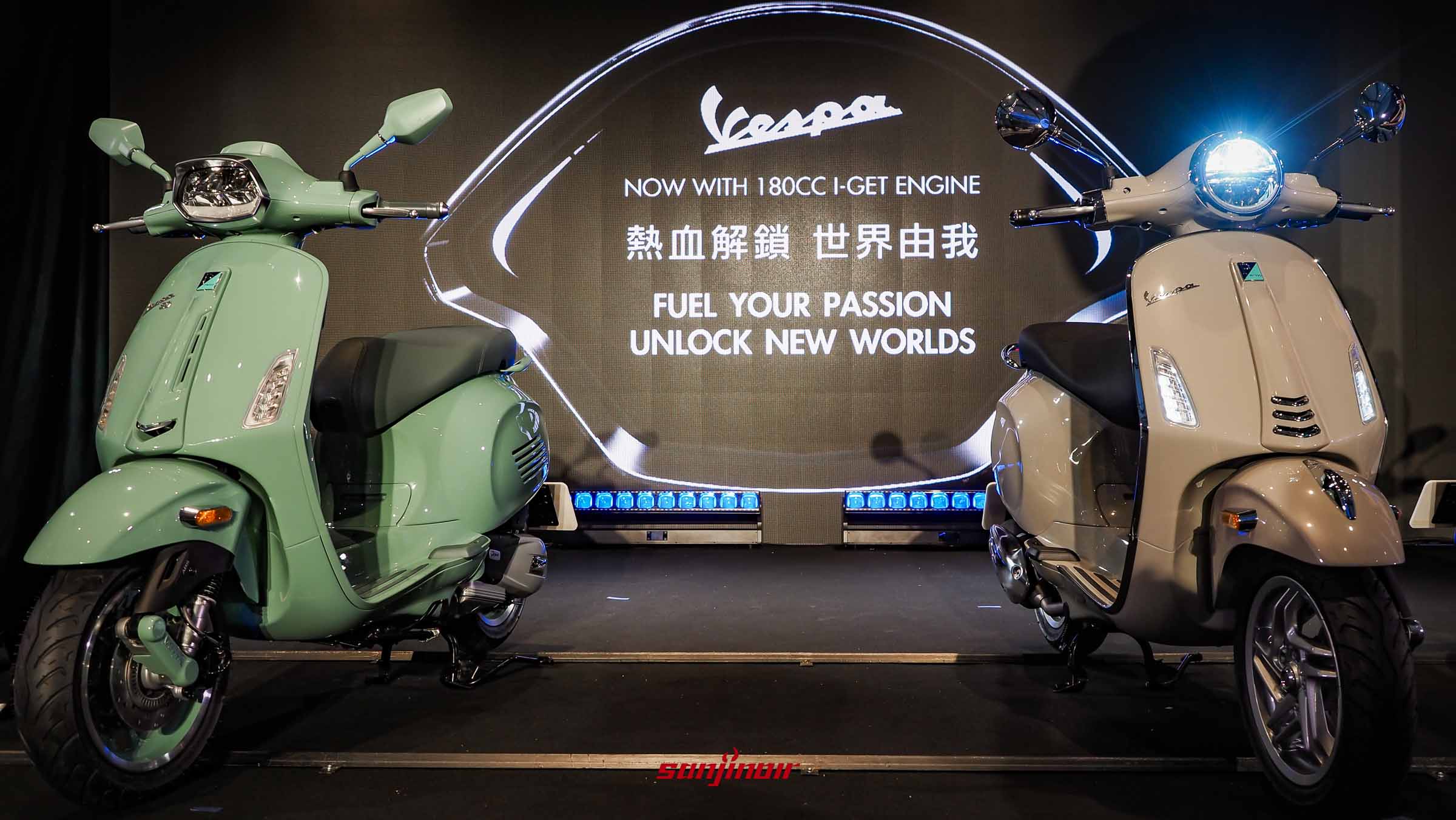 Vespa 80周年發表會舞台，左側為粉彩綠 Sprint 80th，右側為白色 Primavera 180，背景大螢幕顯示著 180c.c. I-GET 引擎宣傳標語與繁體中文「熱血解鎖 世界由我」字樣。