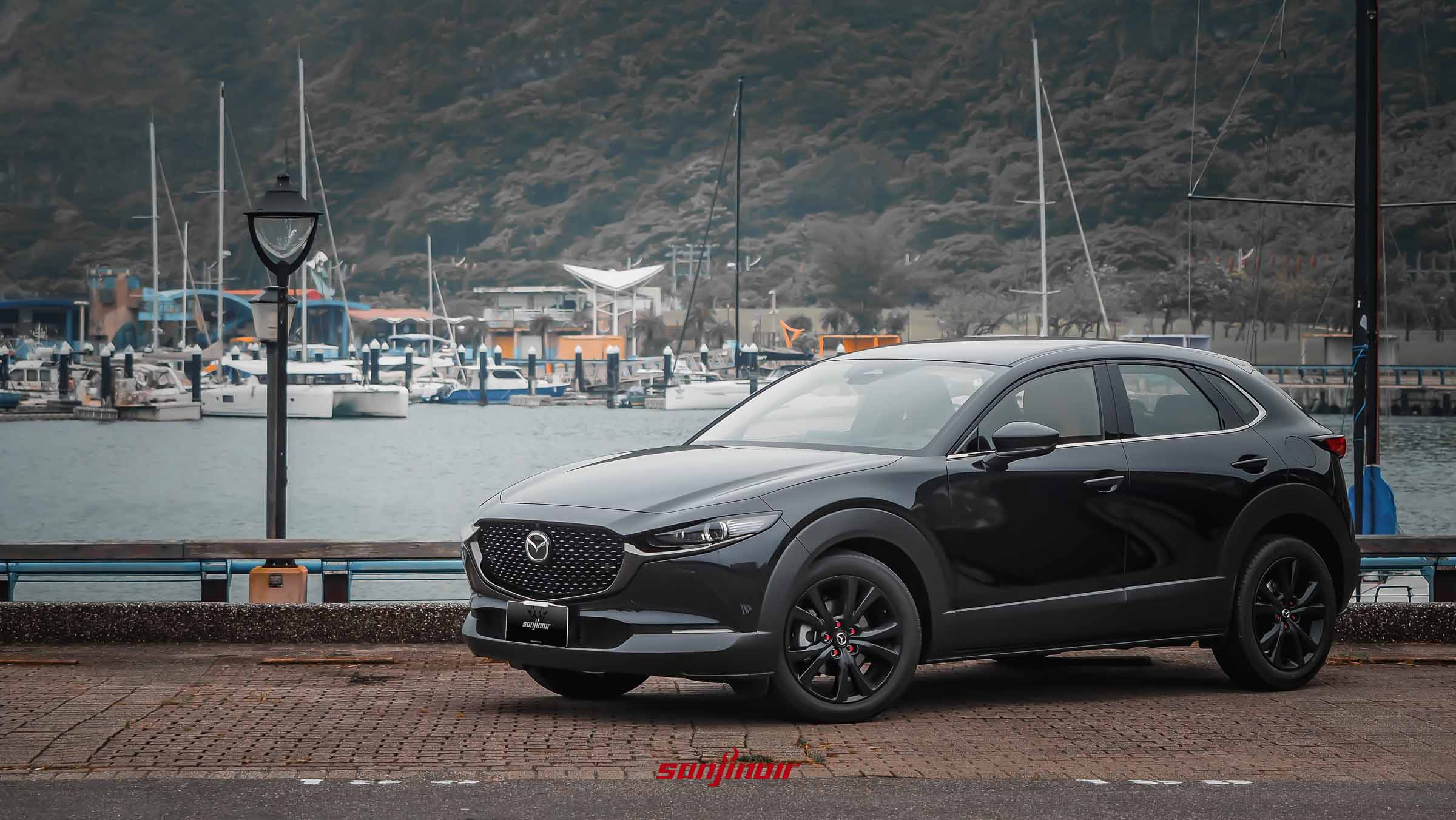 黑色MAZDA CX-30 20S Homura停放於遊艇碼頭旁，展現流線且動感的跨界休旅車身輪廓。