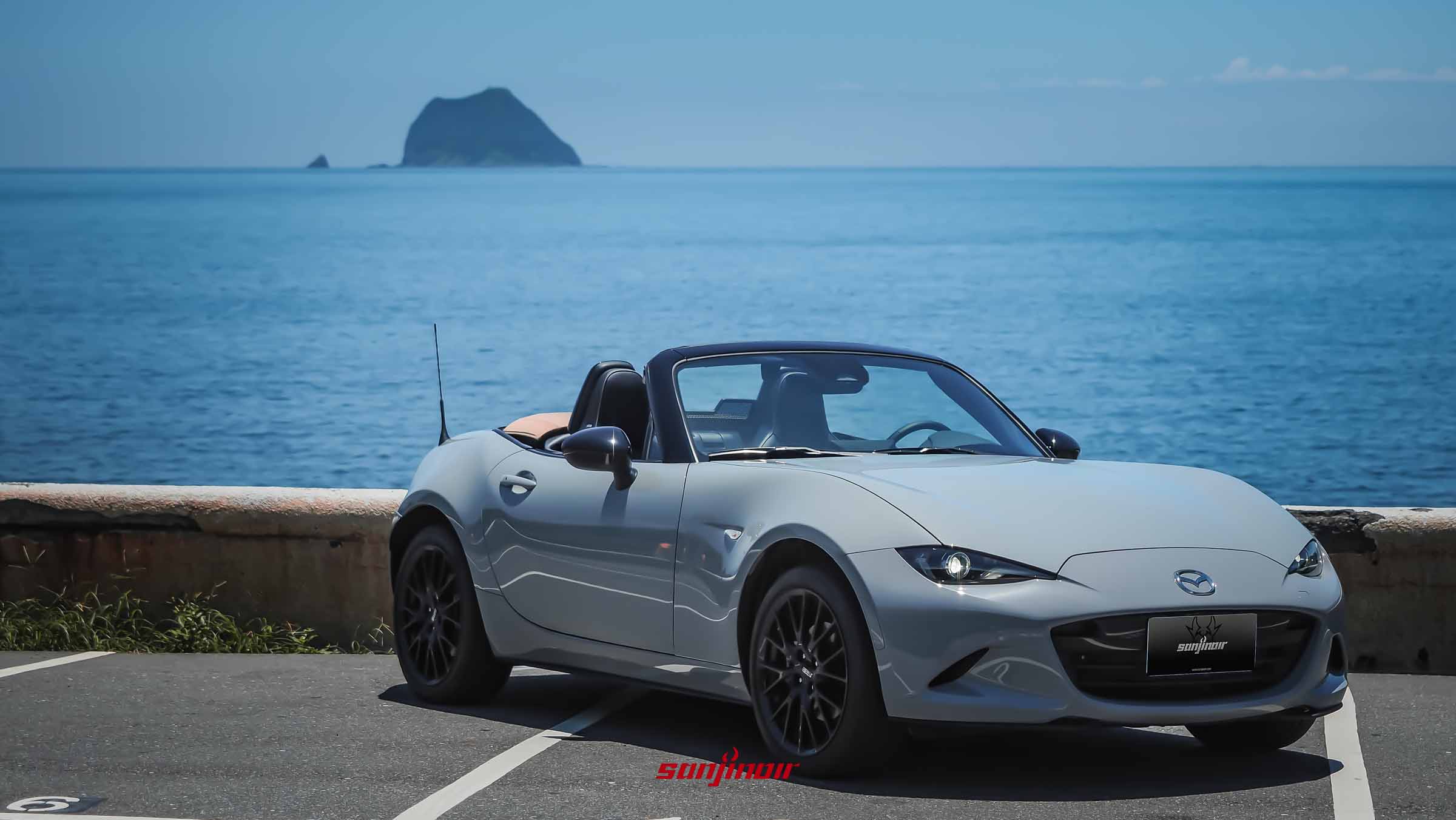 停放於海岸停車場的灰色MAZDA MX-5 RS開篷跑車，背景為湛藍海洋與基隆嶼。
