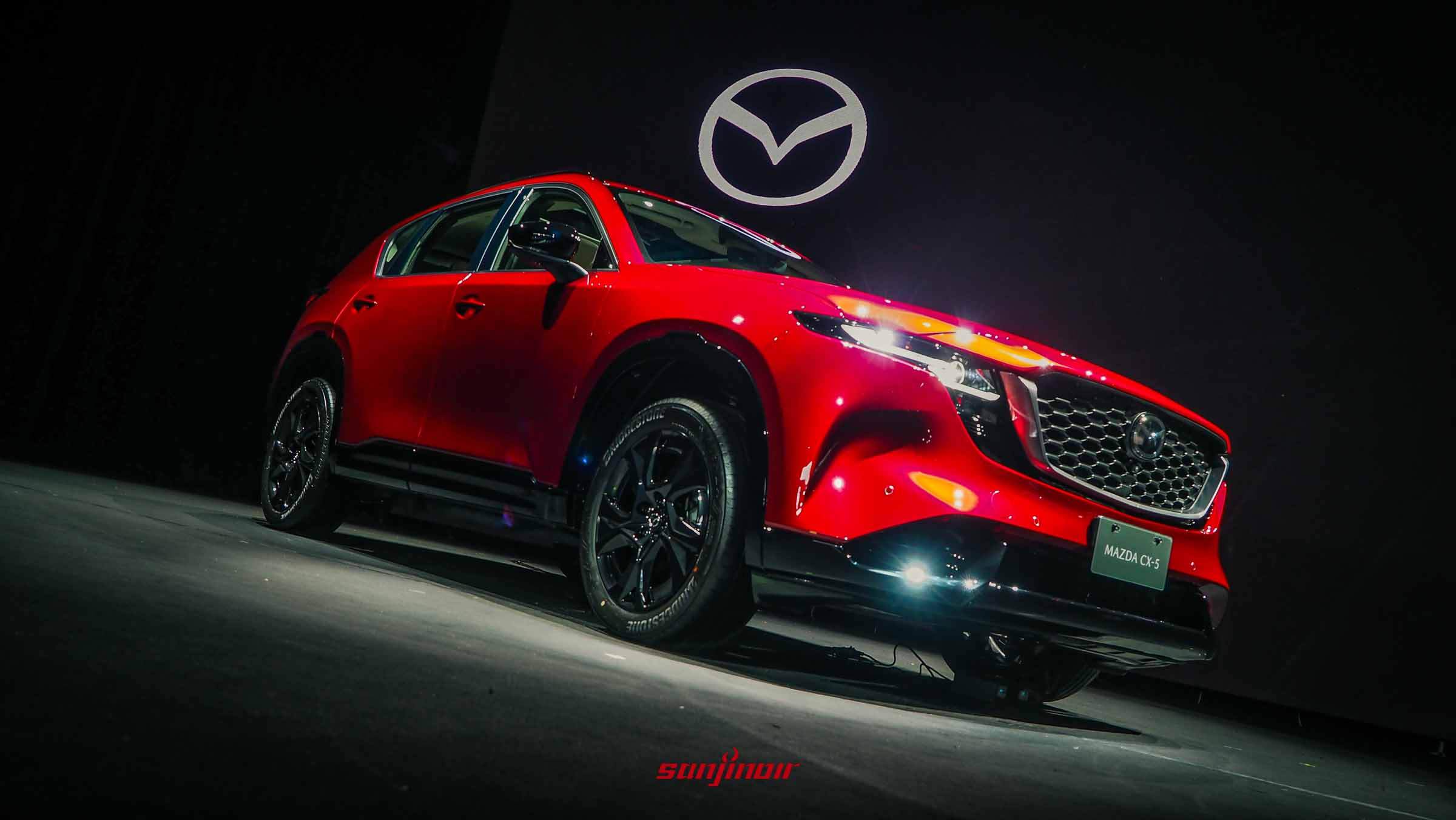 2026全新MAZDA CX-5紅色車款展示於舞台上的右前側視角，展現霸氣且流線的車身輪廓。