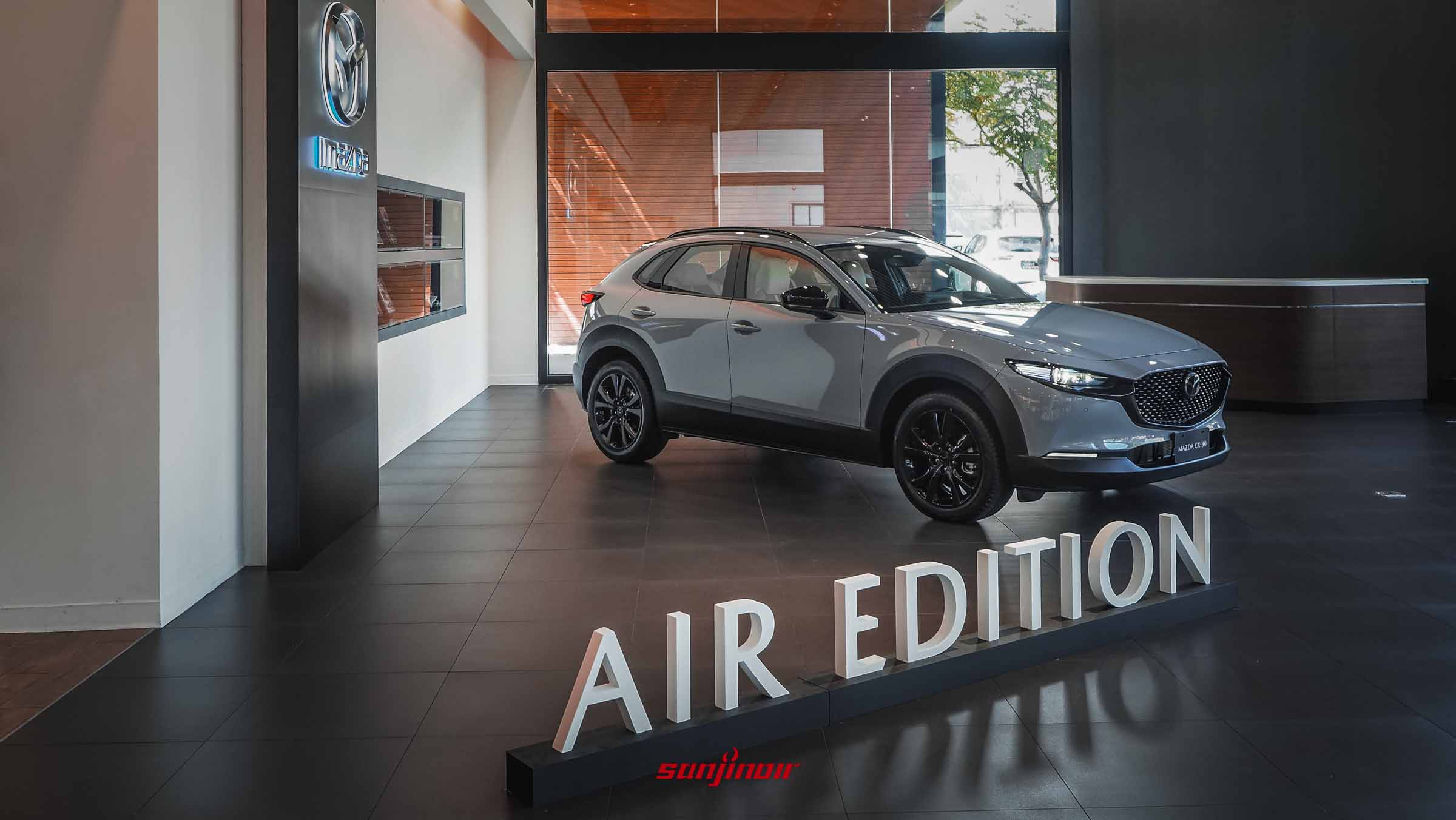停放於展間內的MAZDA CX-30 Air Edition右前方45度角全車照，前方地板擺放著立體的AIR EDITION白色字樣。