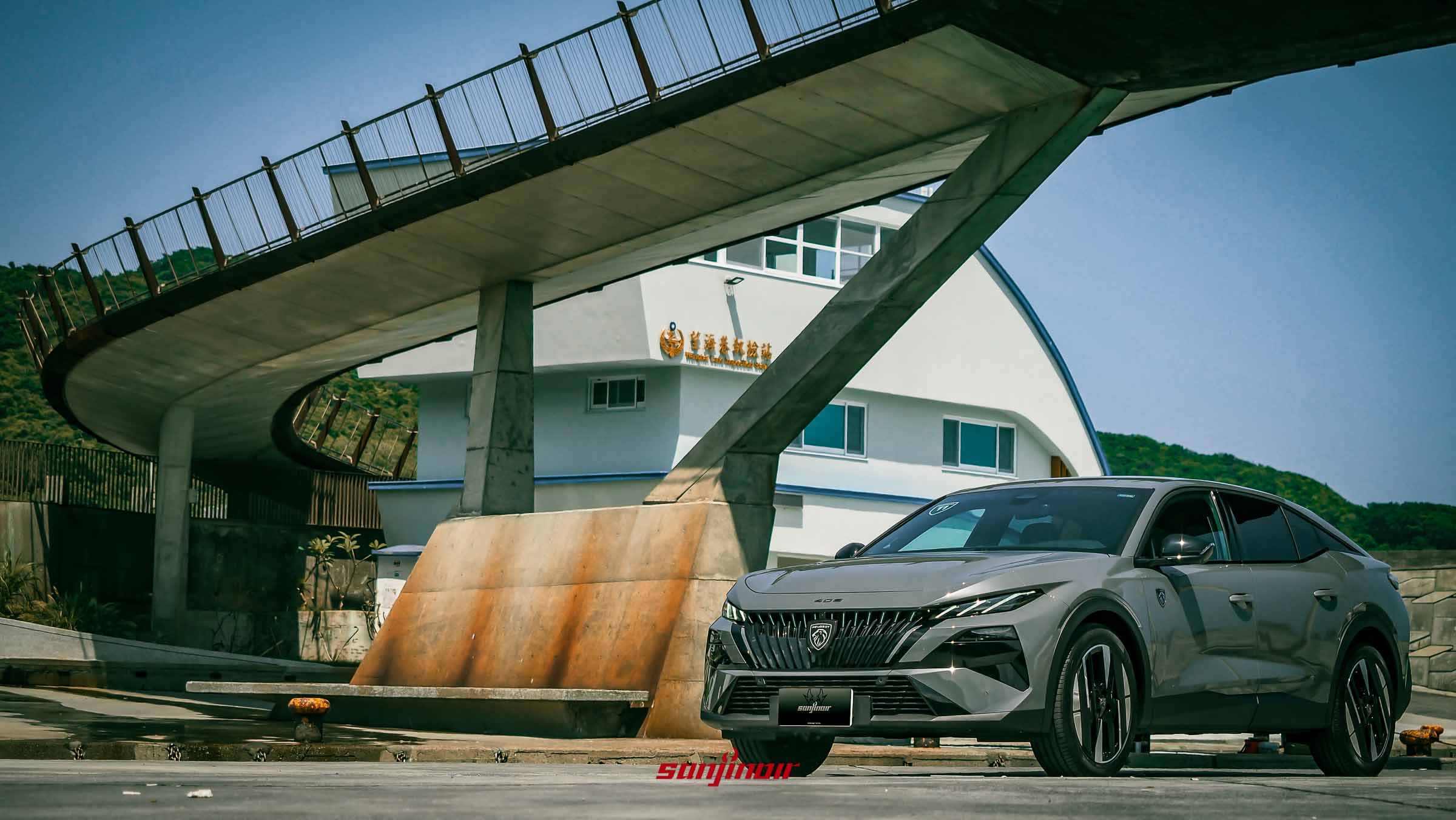 灰色PEUGEOT 408停放在漁港邊，上方有流線型建築結構。