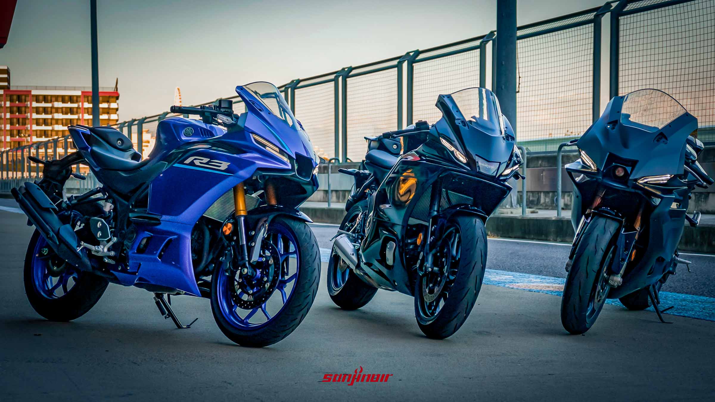 三輛Yamaha YZF-R系列重機停放在賽道旁，由左至右依序為藍色的R3、黑色的R7與黑色的R9，展示出家族化外觀設計。