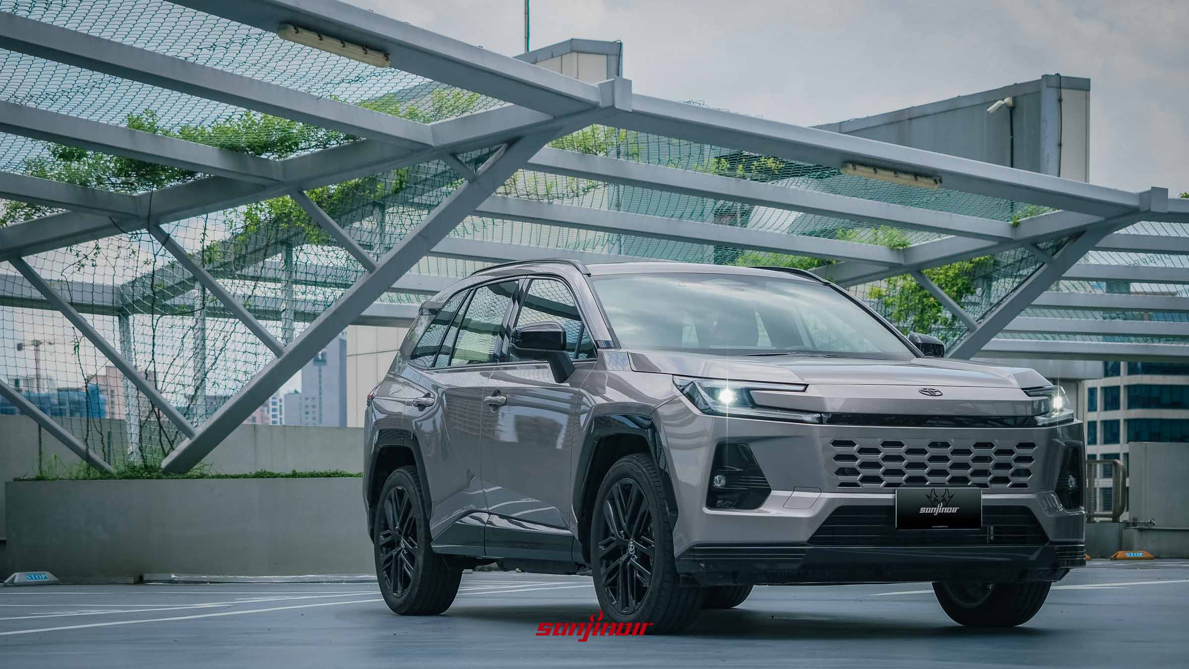 2026 Toyota RAV4 PHEV靜肅灰車色正面偏左視角，停放在立體停車場，展示蜂巢狀水箱護罩與亮黑烤漆下護板。