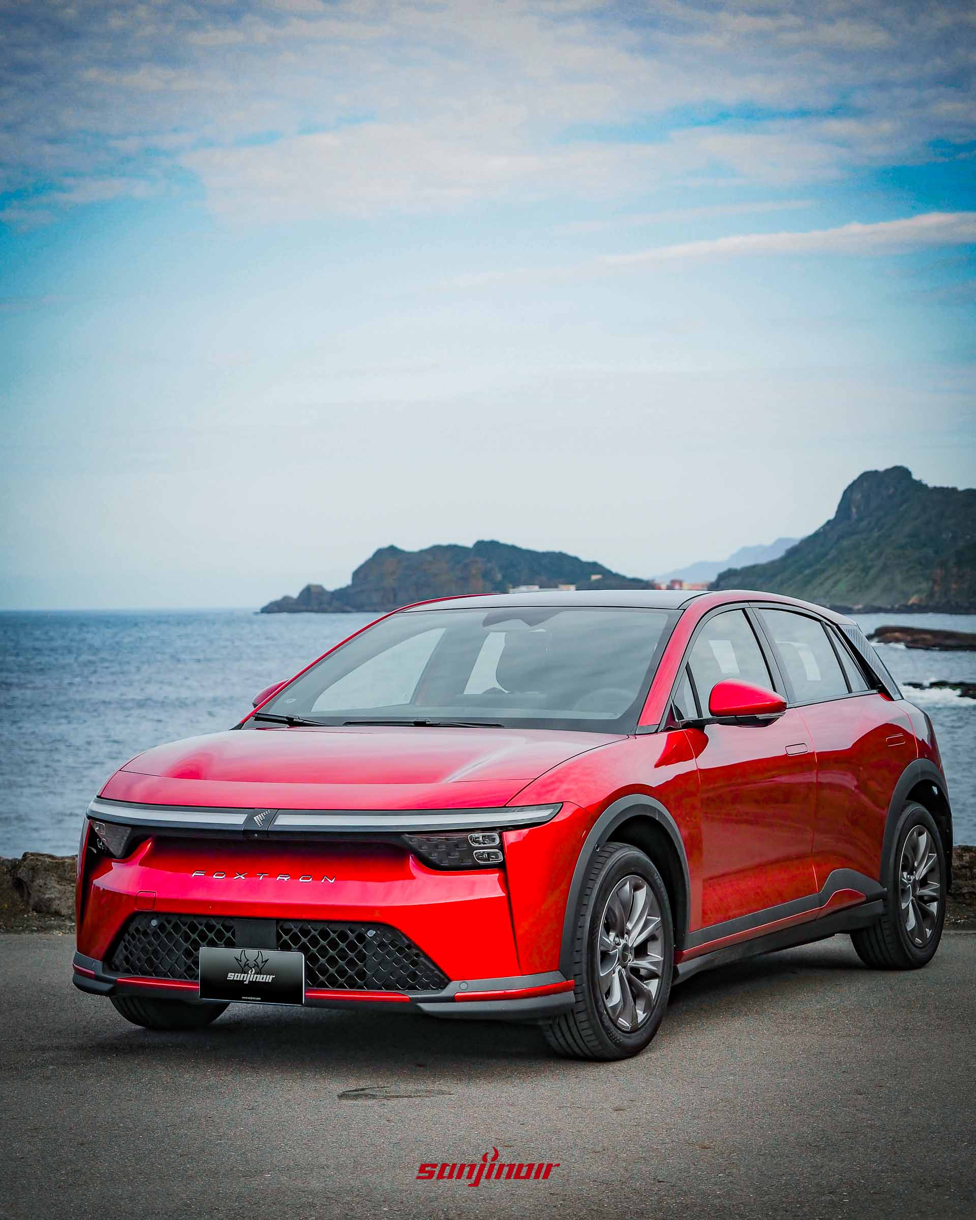 紅色Foxtron Bria Emerge停放在海岸旁的正前側視角照片。