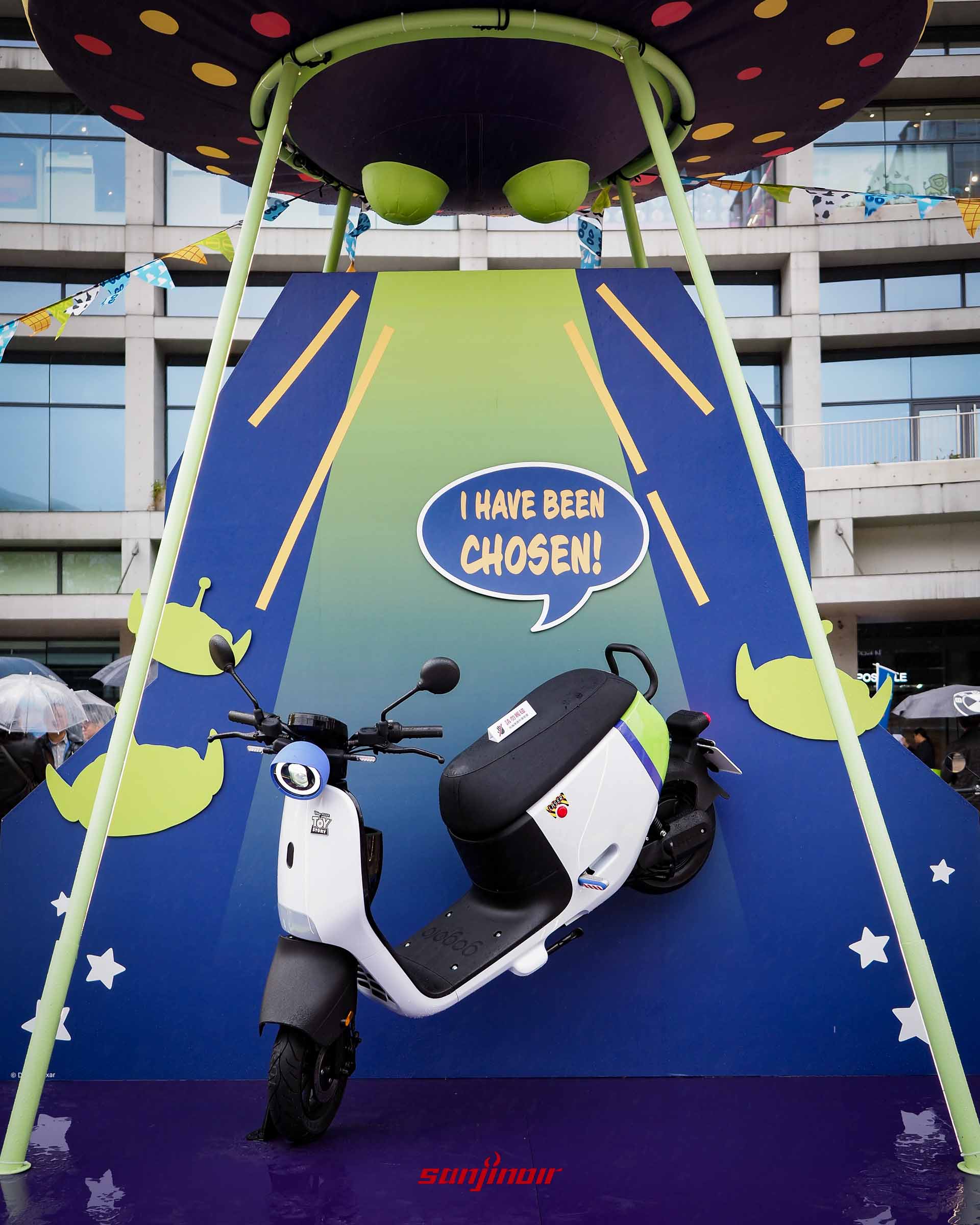 戶外展示的Gogoro EZZY 500浩瀚宇宙號機車，上方有巨型飛碟造景與三眼怪看板。