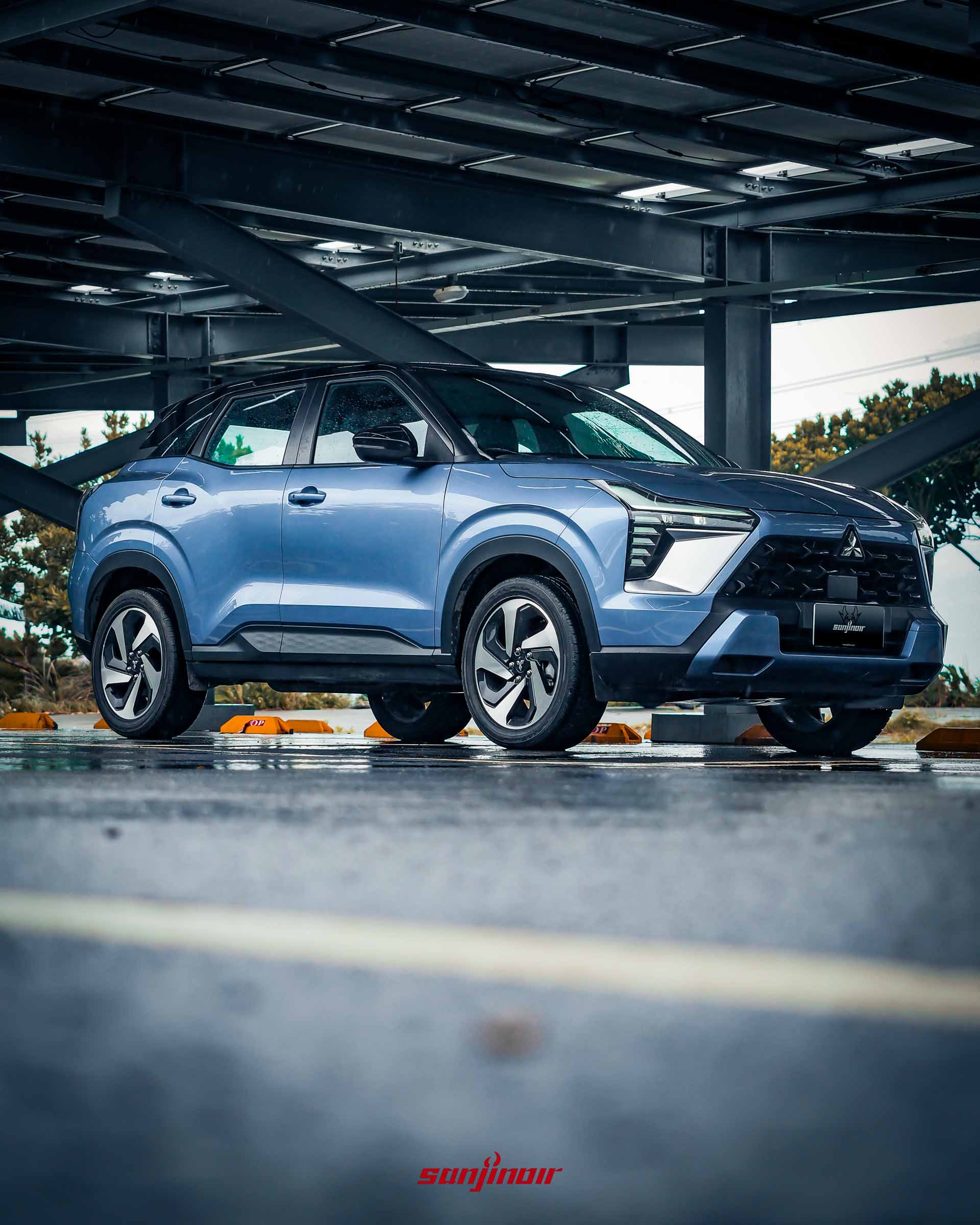 藍色Mitsubishi XForce狂享版停放於雨後的太陽能板棚架下。