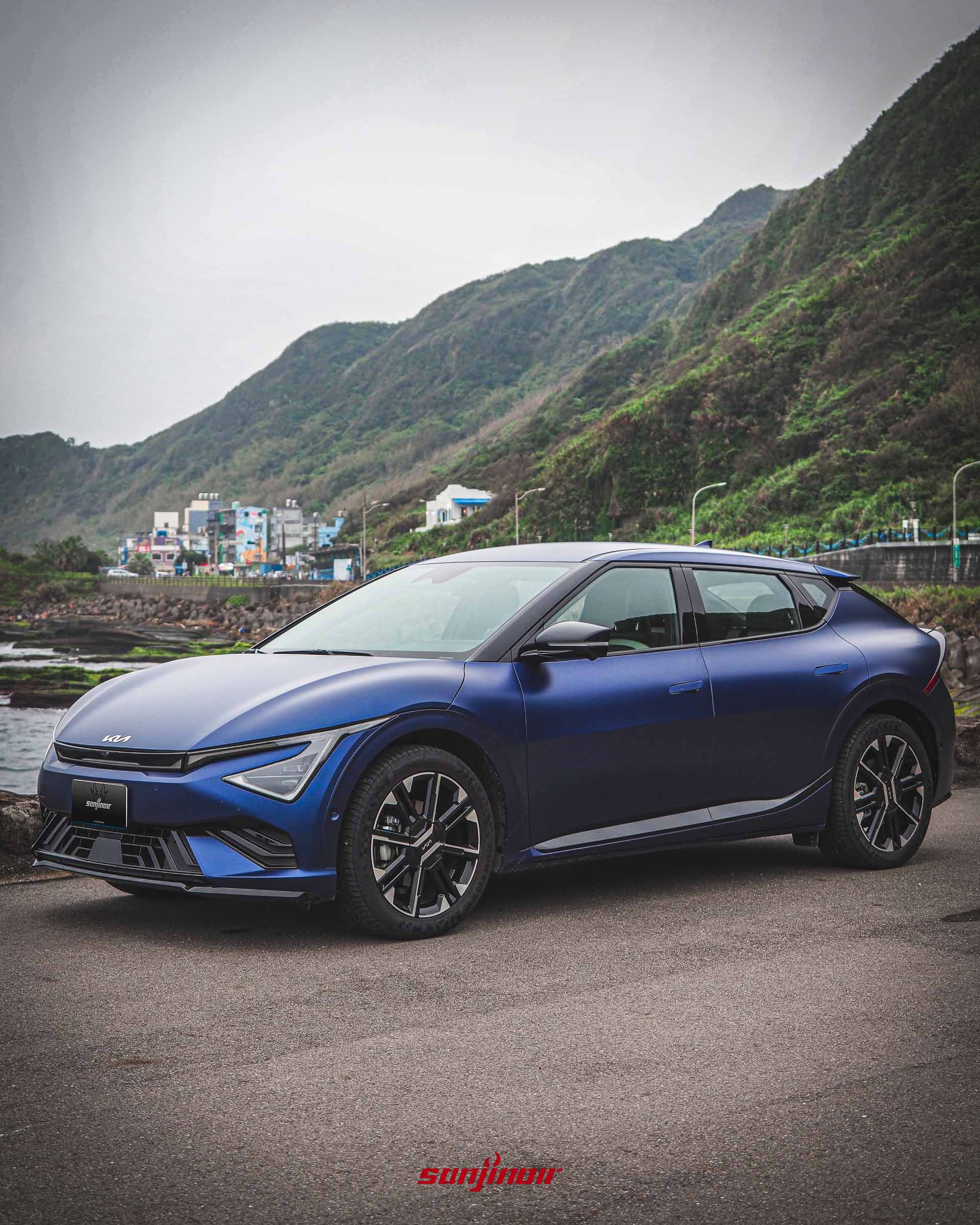 藍色啞光Kia EV6 GT-Line電動車正面3/4視角的照片，停在海邊位置。