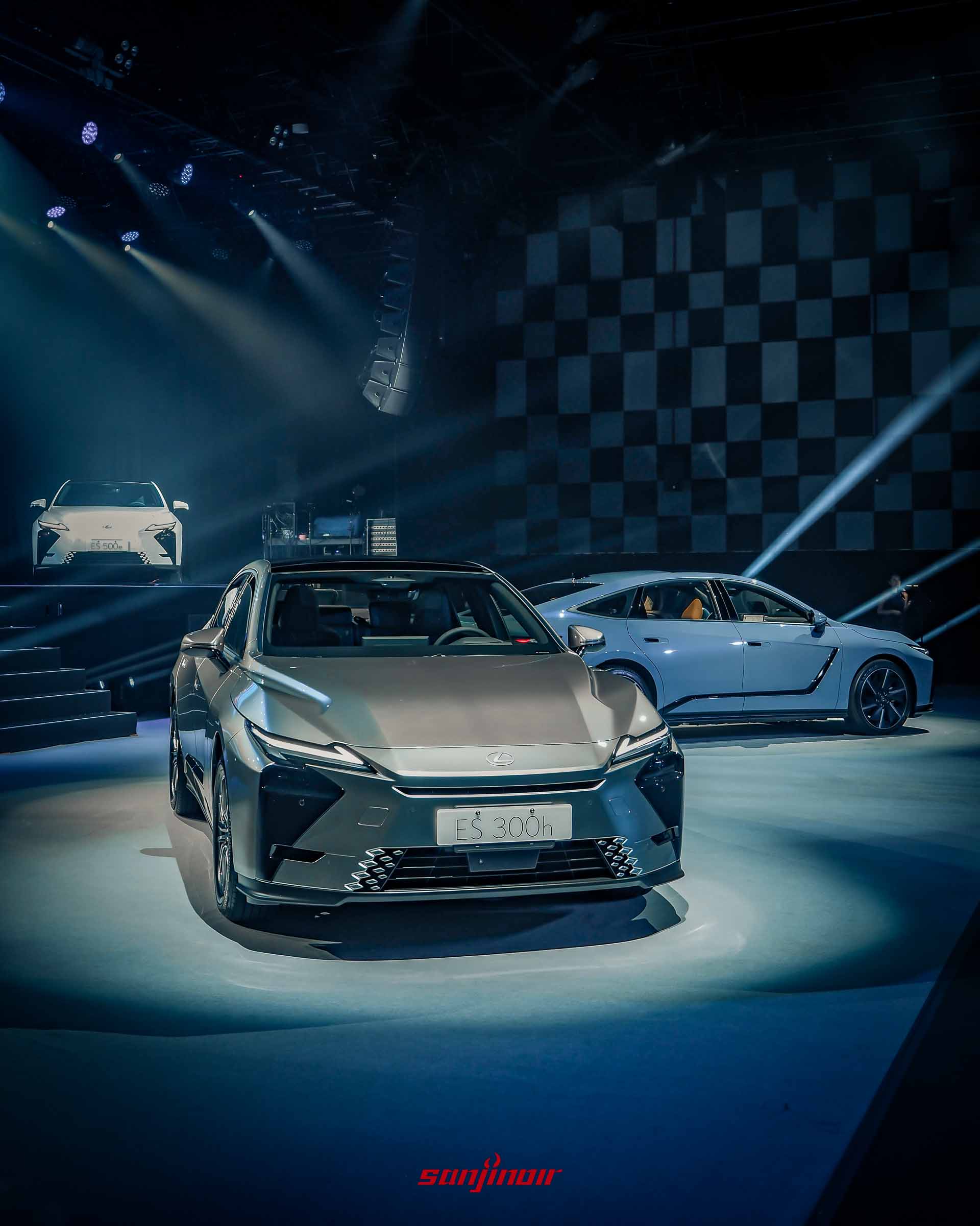 三輛不同顏色的Lexus ES停放在發表會舞台上，最前方為銀色ES300h，右側為淺藍色車型，左後方為白色純電ES500e。