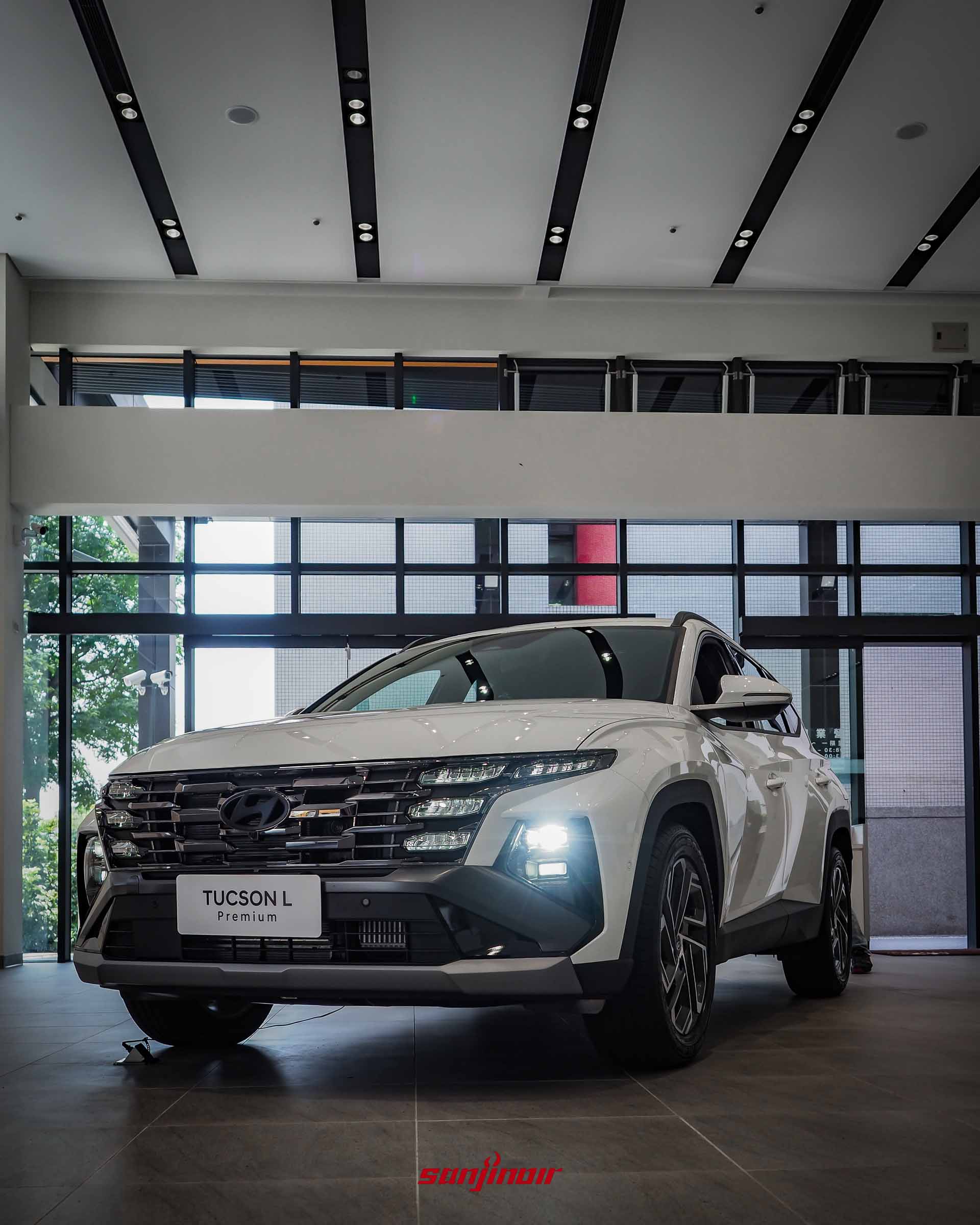 低角度拍攝的白色2026 HYUNDAI Tucson L 26.5年式Premium休旅車正面照,頭燈正點亮運作中,呈現強烈視覺張力。
