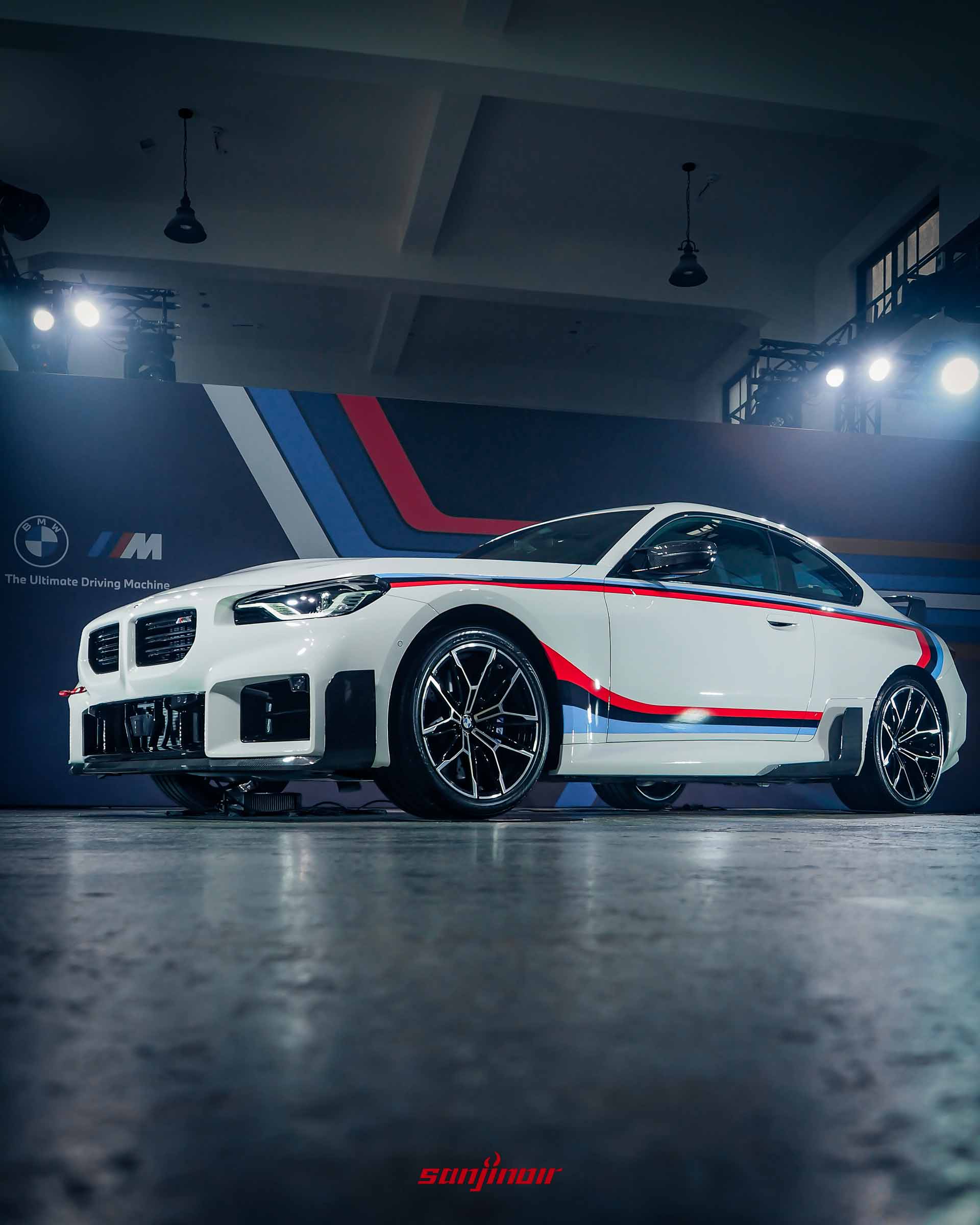 視角較低的白色BMW M2特仕版右前方外觀照，凸顯前保桿碳纖維定風翼與紅色專屬拖車繩。