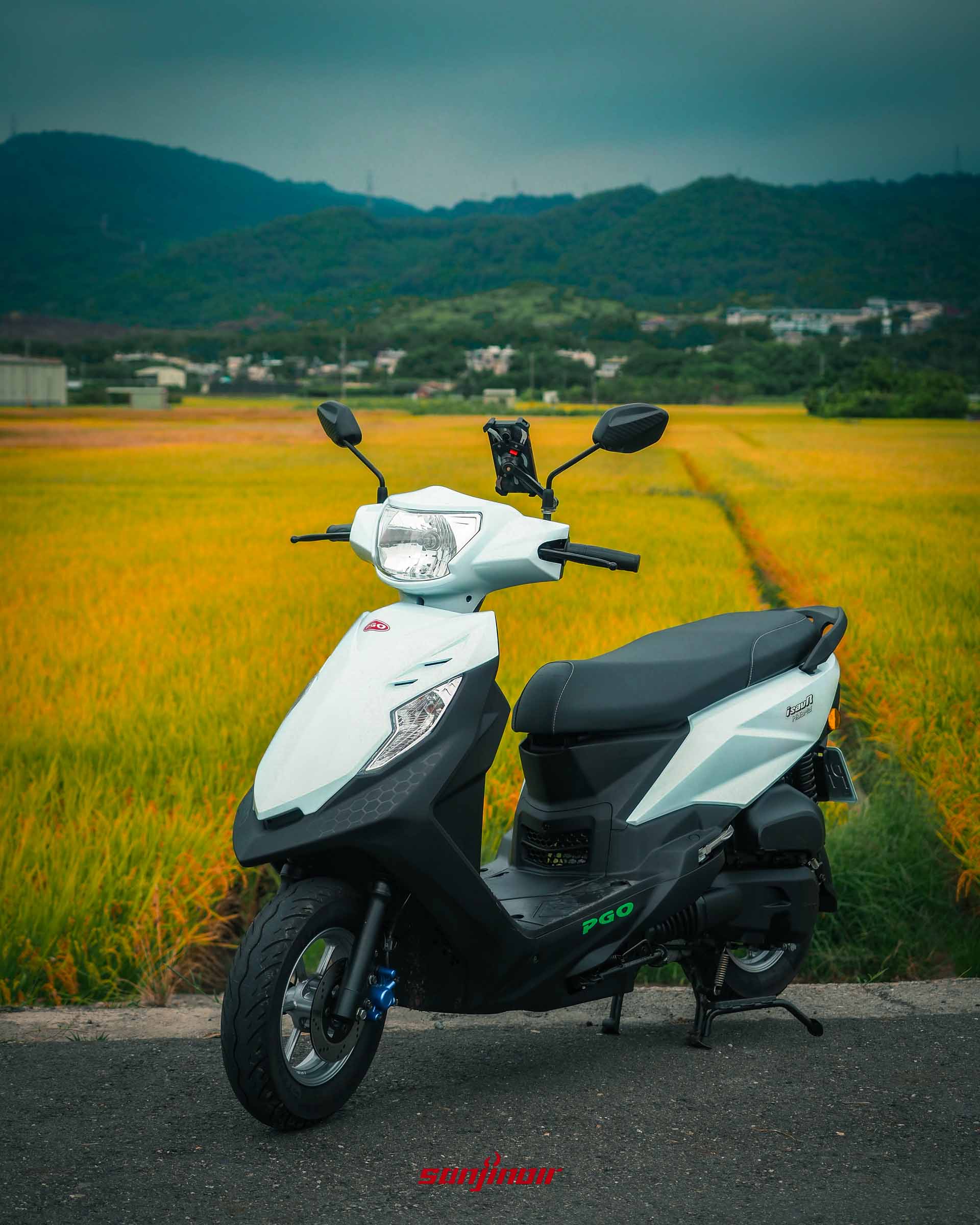 直式構圖的白色PGO isavR威力125,座落於金黃色稻田旁的鄉道上。
