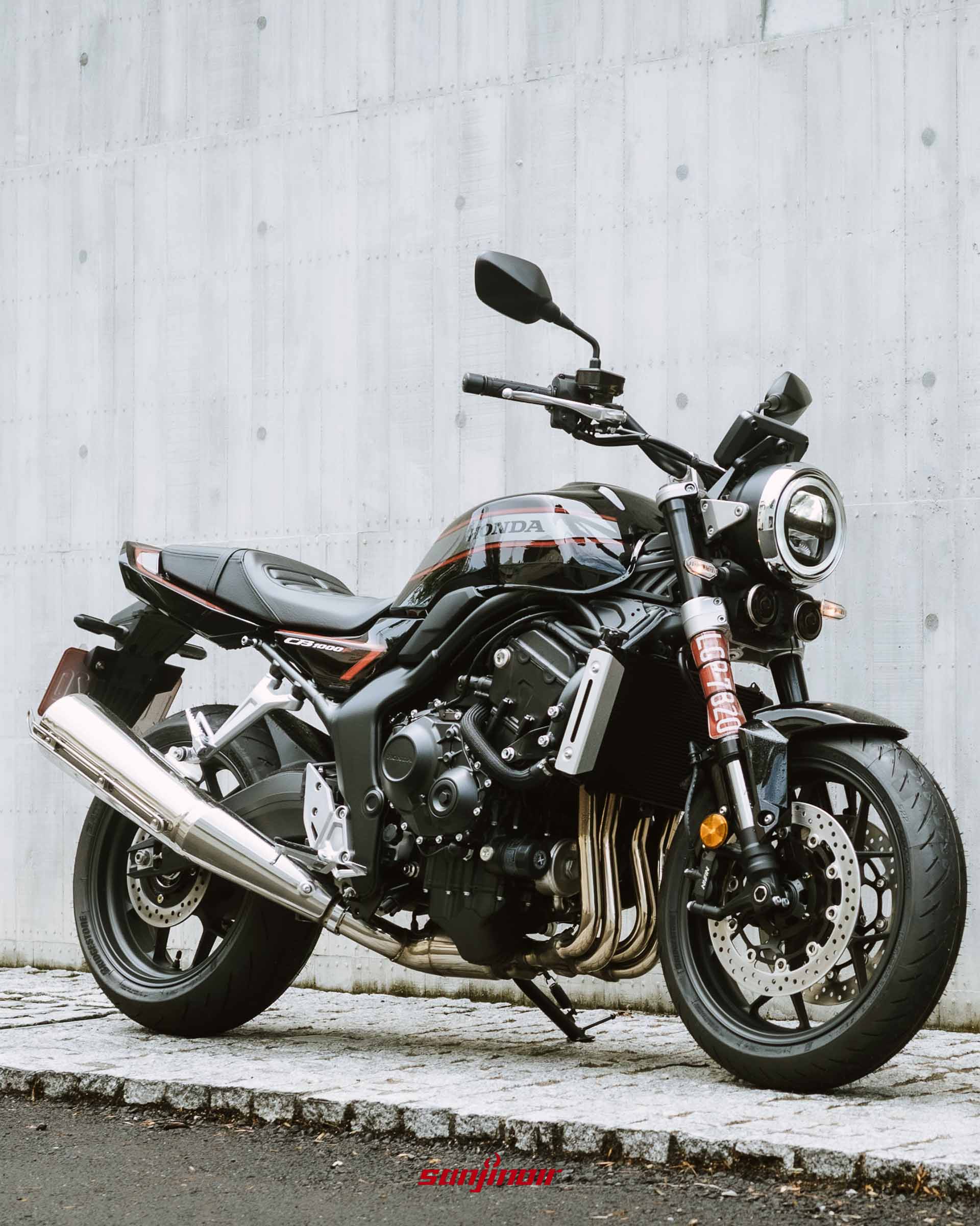 黑色Honda CB1000F停放於清水模牆面與石板路上的右前側視角照片。