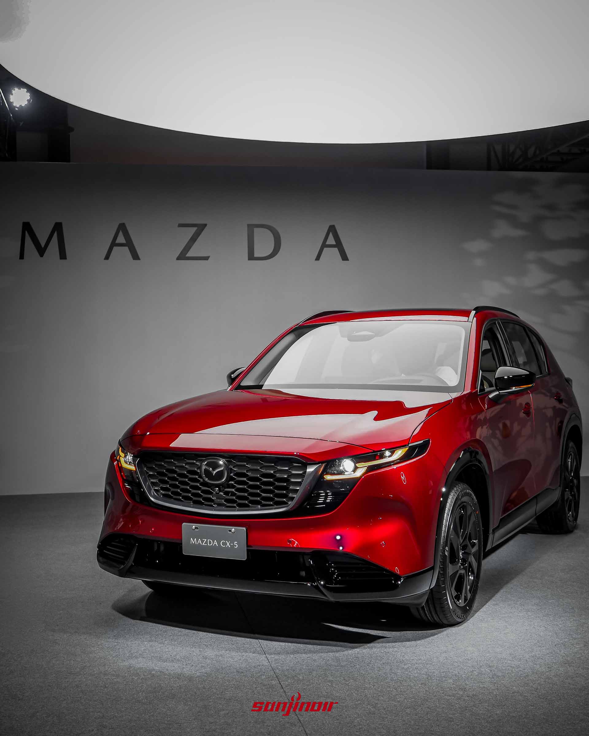 紅色MAZDA CX-5前側45度角視覺，展示車頭水箱護罩與俐落的車身線條，上方有圓形照明燈光。