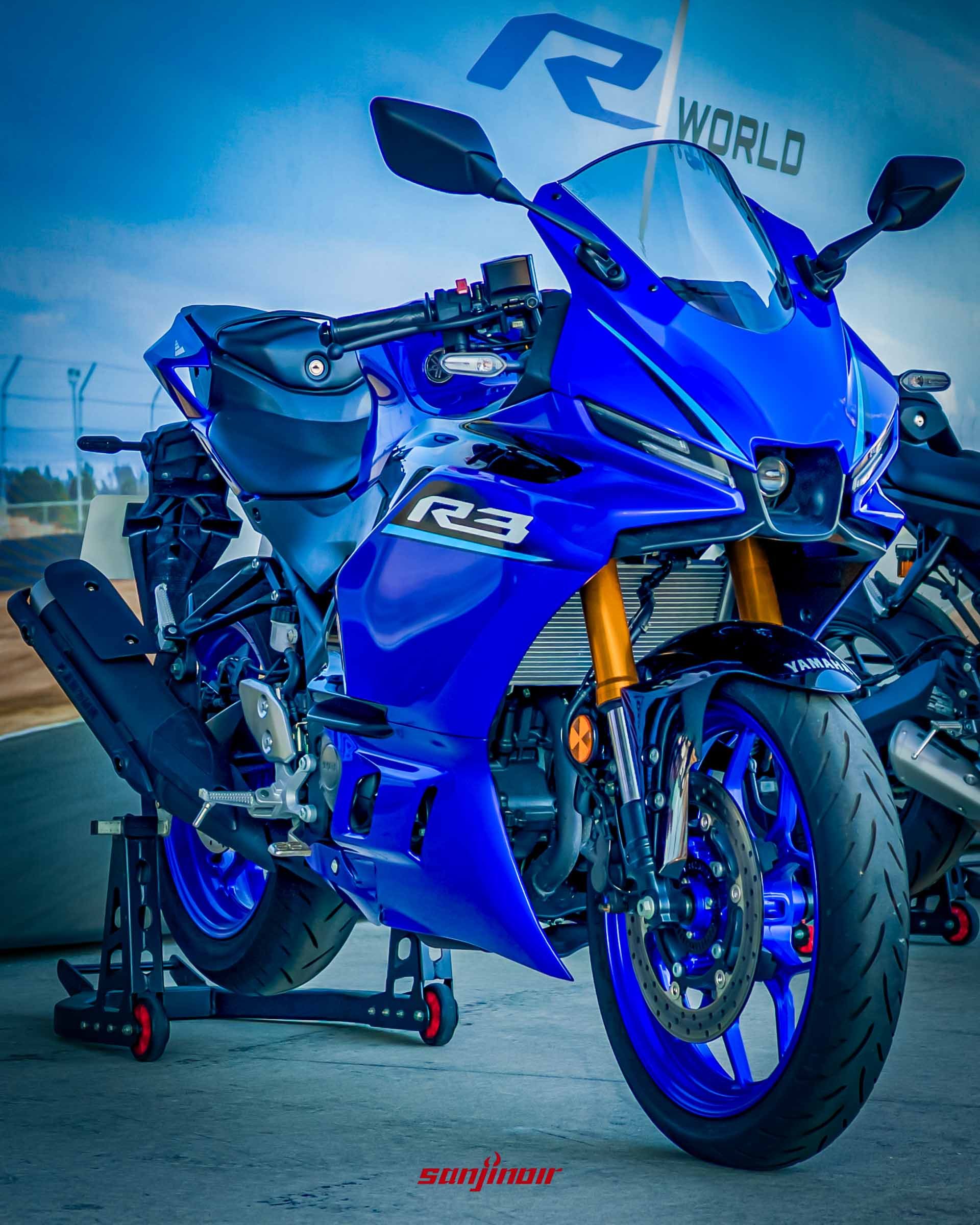 一輛藍色的Yamaha YZF-R3停放在駐車架上,背景帶有R World字樣,車身線條充滿運動感。