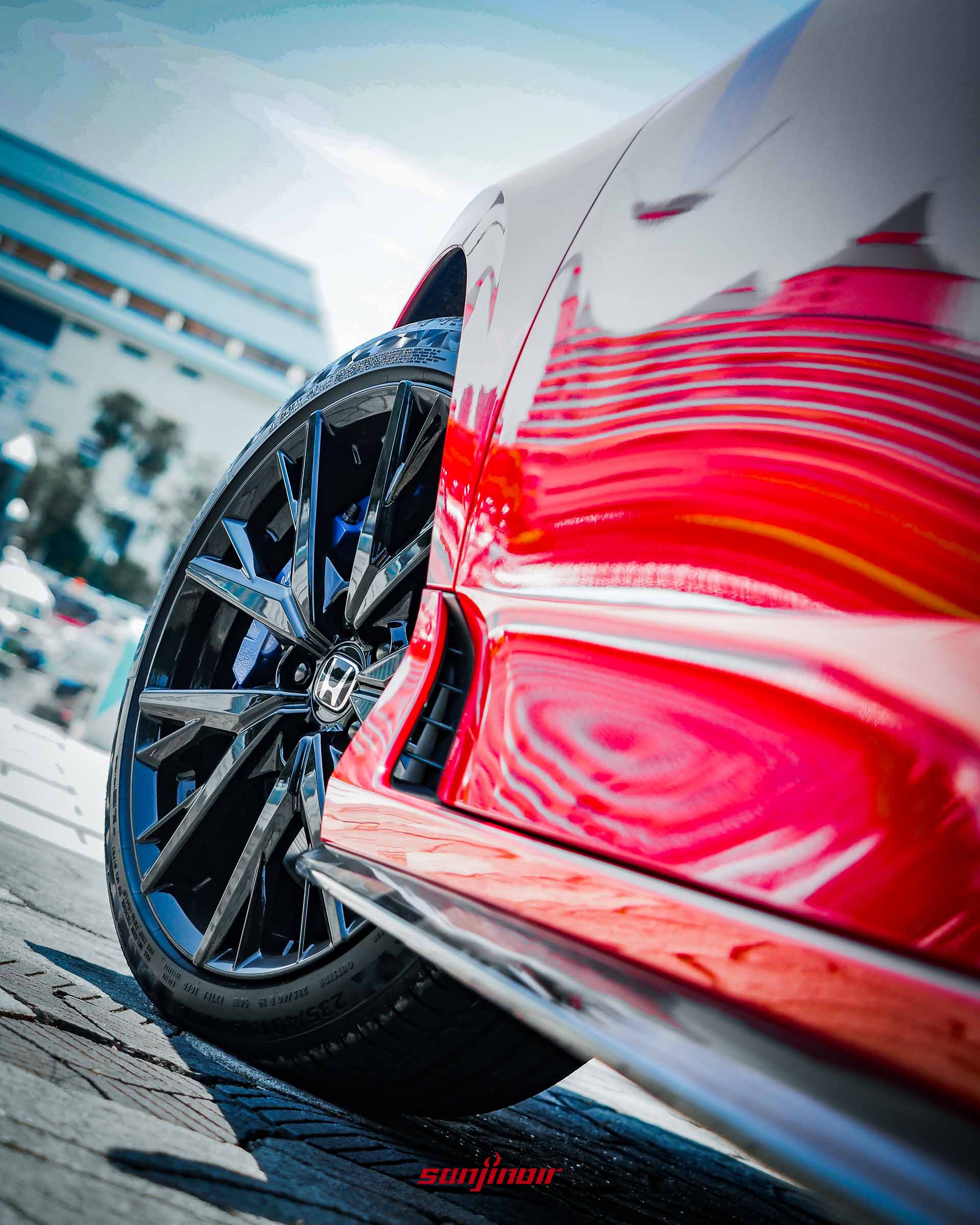 特寫紅色HONDA Prelude的前輪框與Brembo藍色煞車卡鉗,車身烤漆反射出周遭建築的倒影。