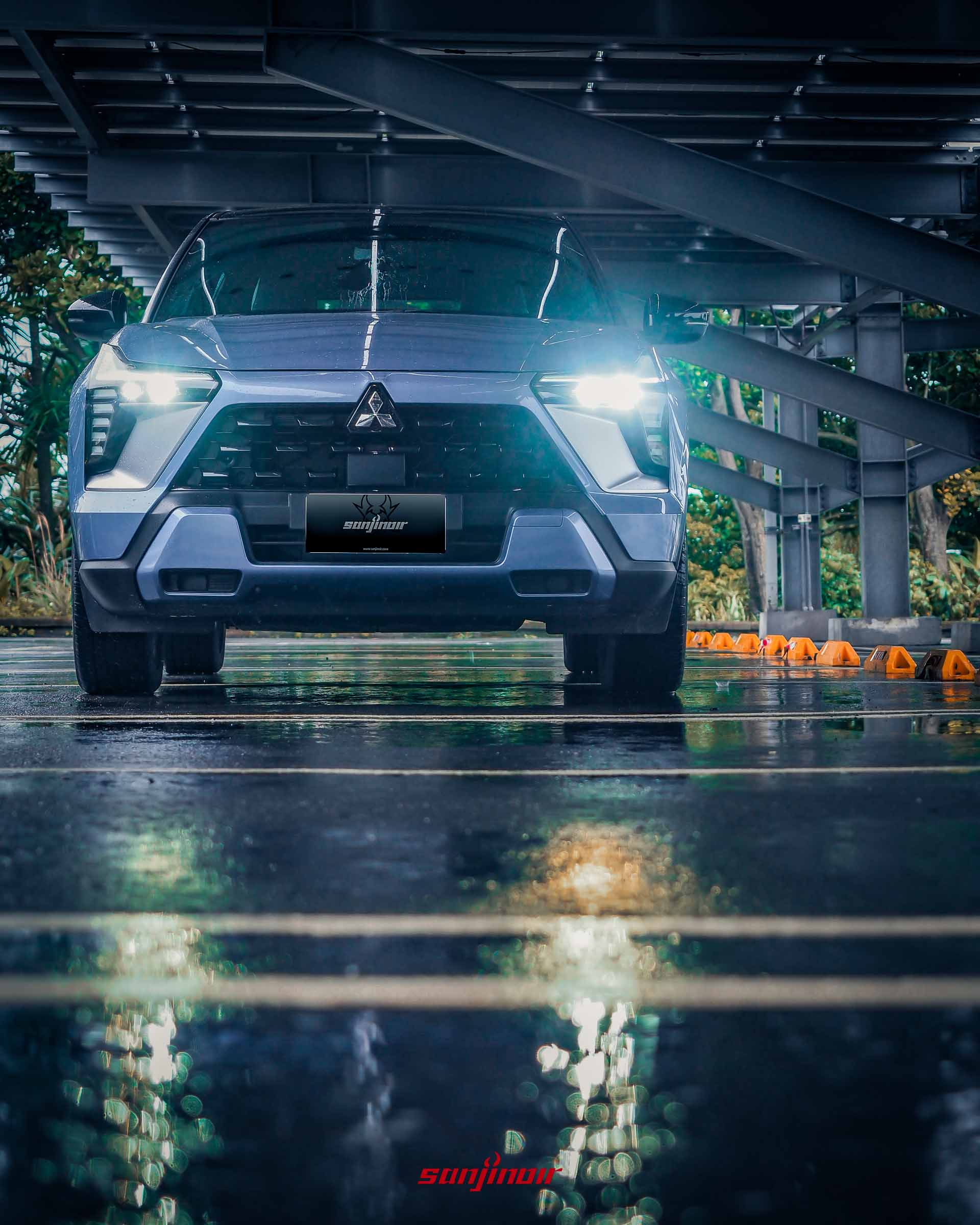 Mitsubishi XForce狂享版車頭特寫，頭燈亮起並倒映於濕滑地面。