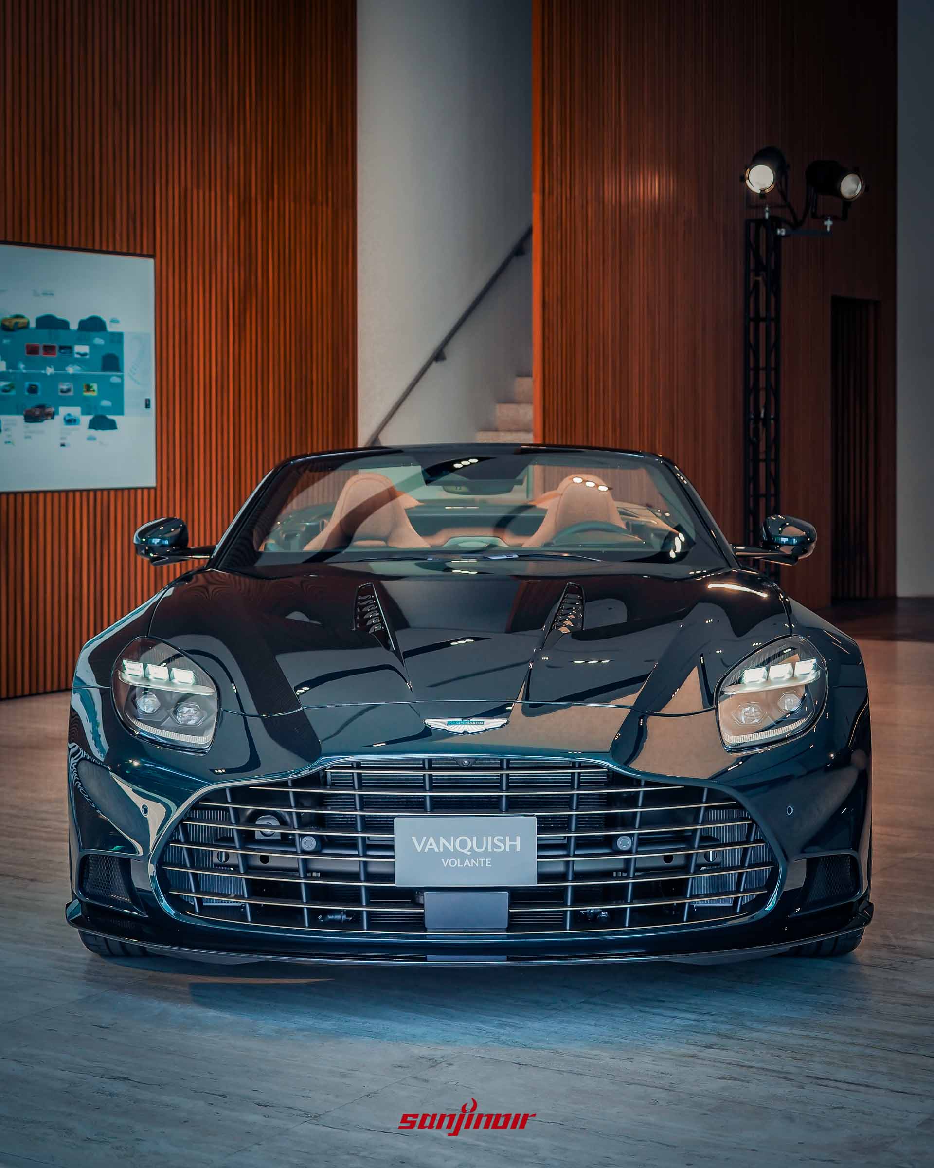 Aston Martin Vanquish Volante 60th Anniversary Edition 敞篷車的正前視角，Pentland Green 漆色。銳利的 LED 大燈，黑色凸字型水箱護罩，展现其正面狂傲的眼神。