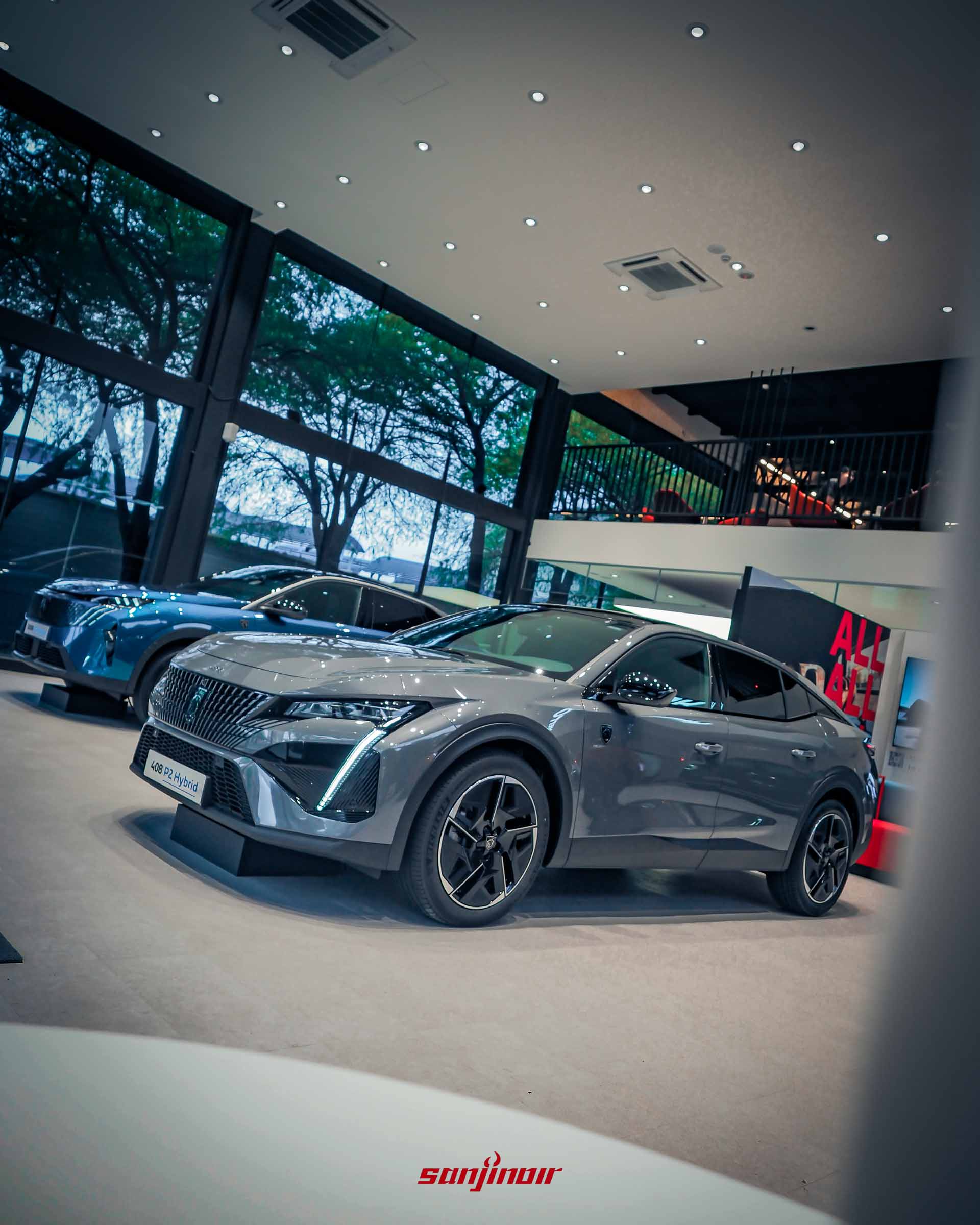 一輛灰色 PEUGEOT 408 P2 Hybrid 的對角線視角。車輛具有光滑的轎跑車流線型線條，大型多幅合金輪圈和垂直日行燈。