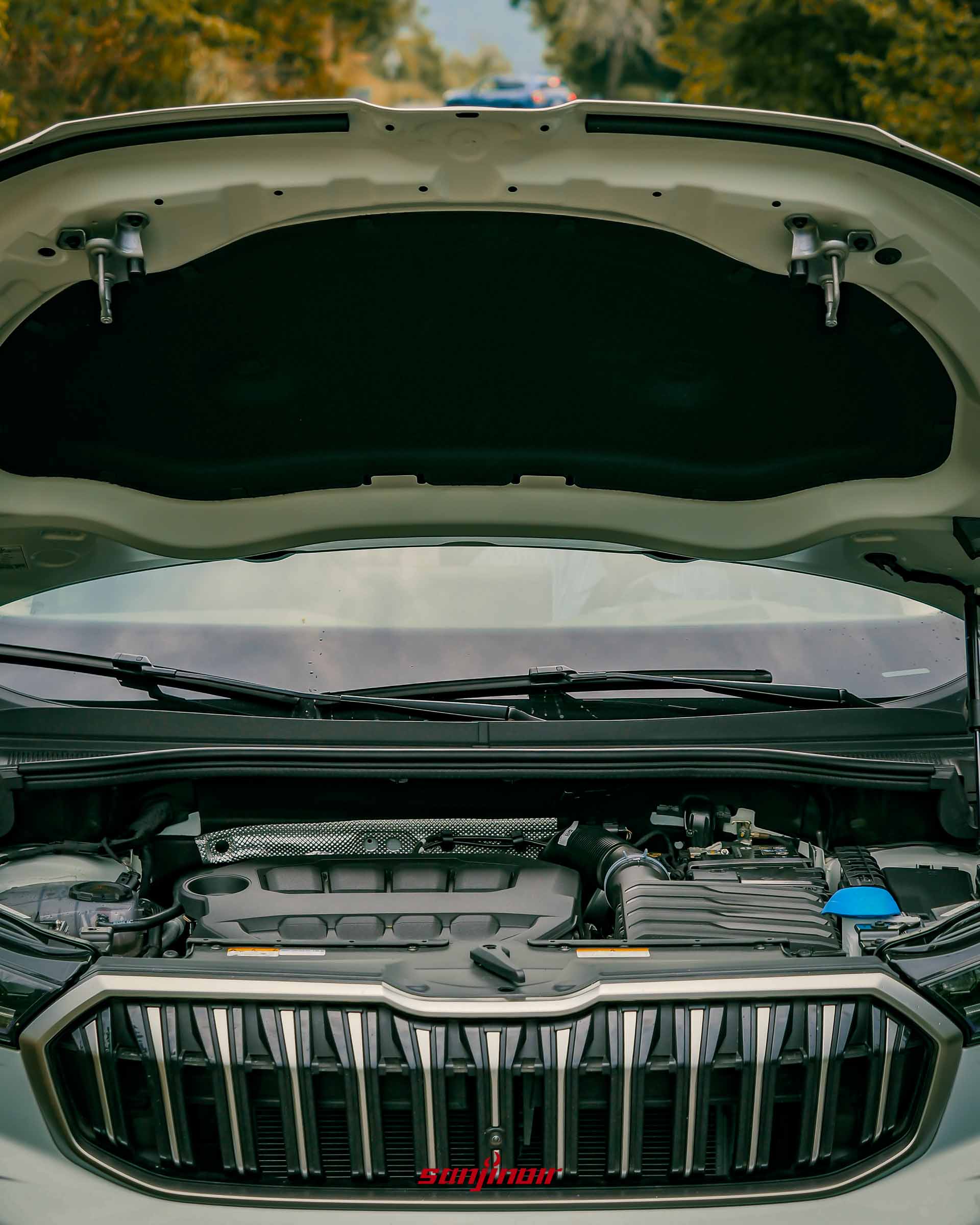 打開 Škoda Kodiaq 2.0 TSI 4×4 引擎蓋的特寫照片，顯示 EA888 Evo4 2.0升渦輪增壓引擎。背景是礫石路和模糊的藍色 Octavia Combi。