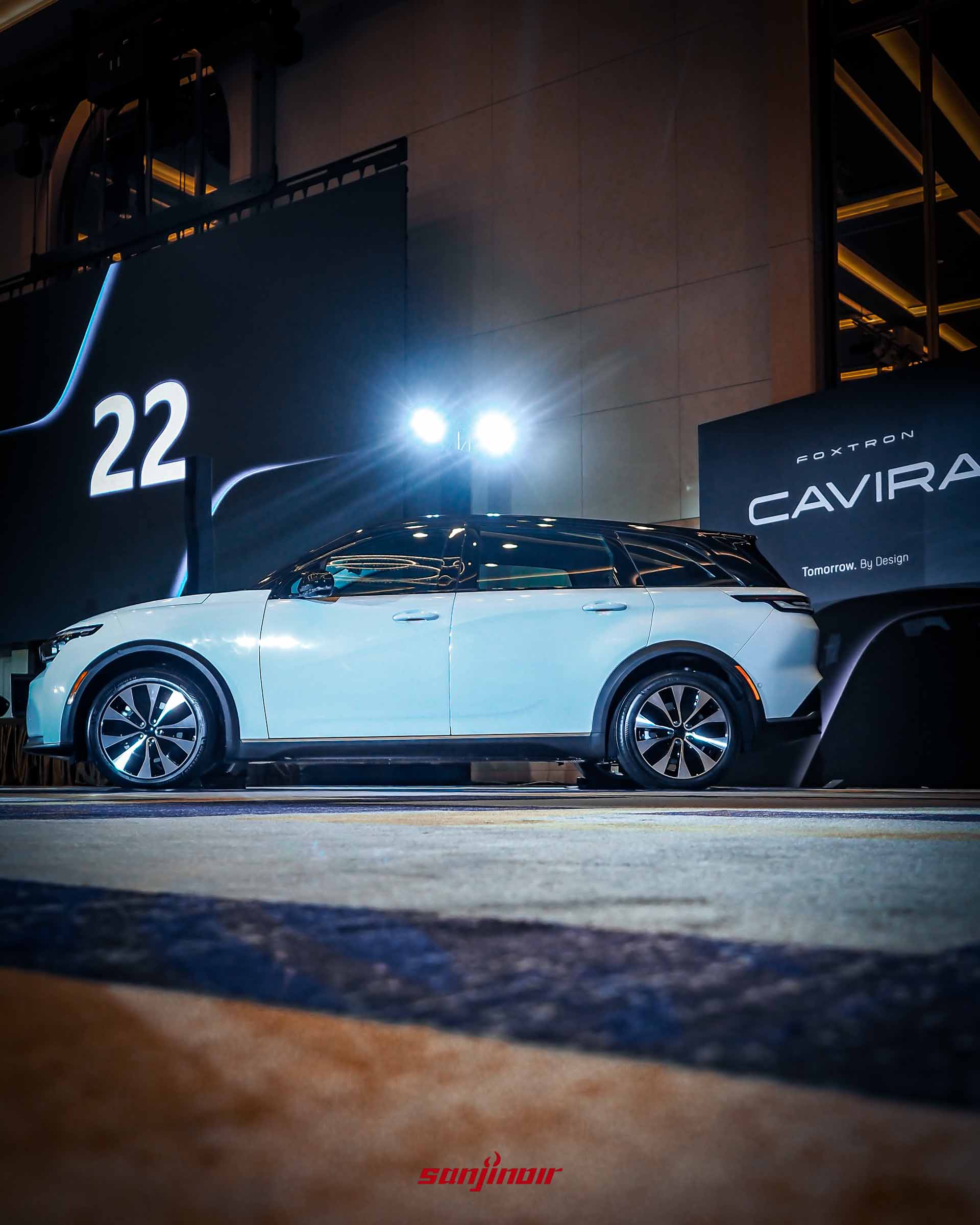 白色Foxtron Cavira側面全車照,背景為大型發表會螢幕,展示車身側面平整流線的輪廓。