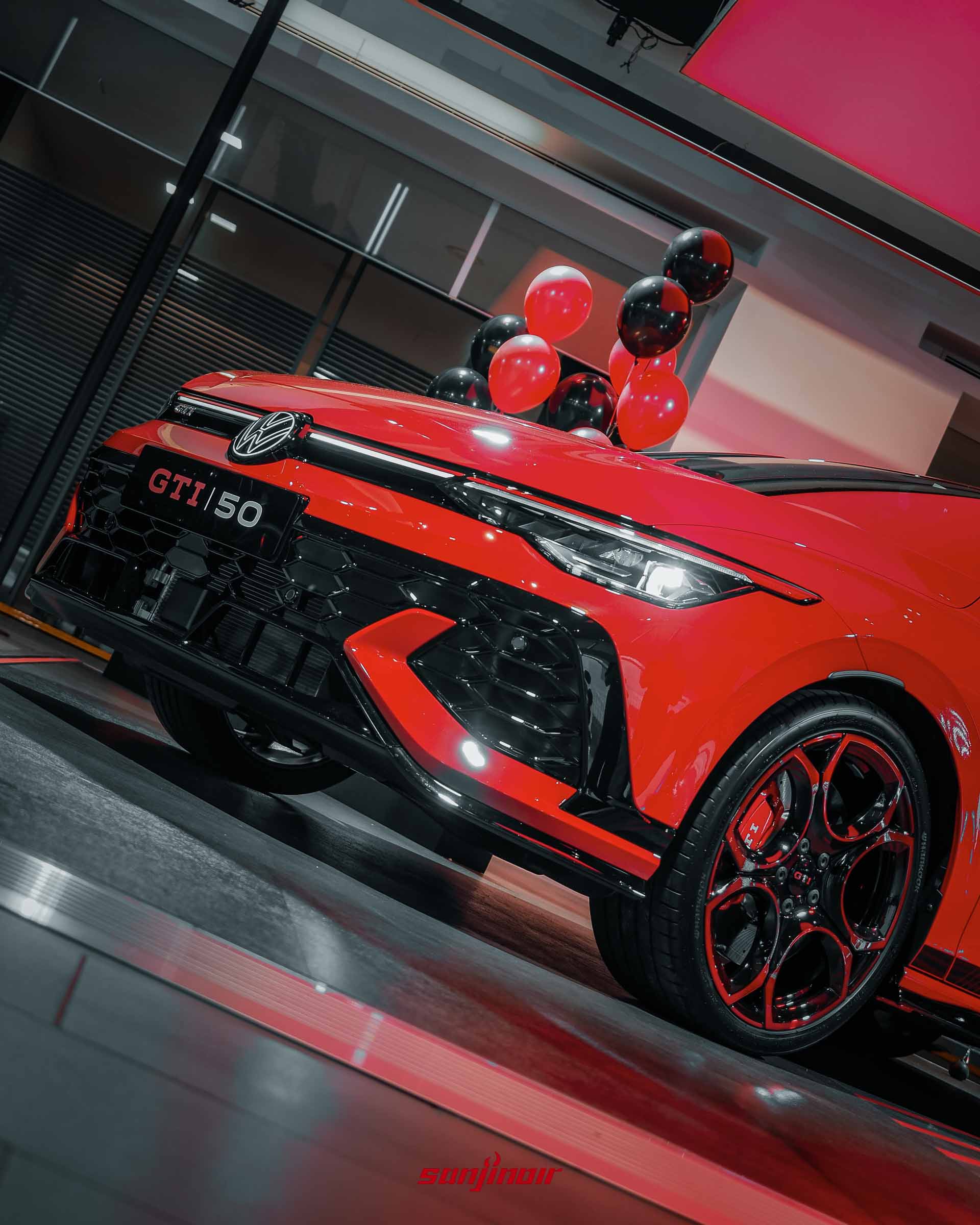 低角度拍攝的Golf GTI EDITION 50車頭與右前輪特寫，強調蜂巢狀氣壩與專屬黑化前保桿的銳利線條。