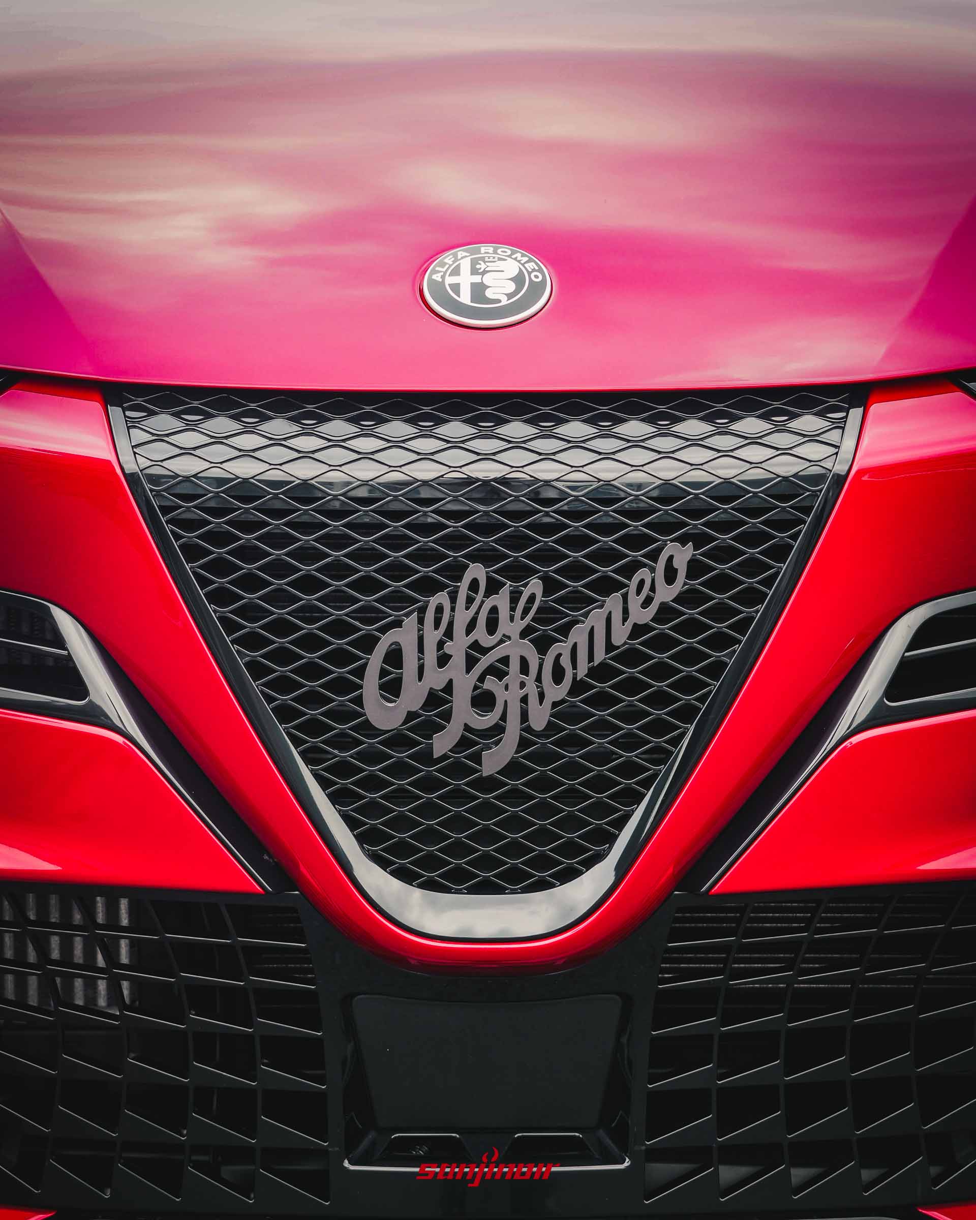 Alfa Romeo Junior紅色車頭特寫,清楚顯示倒三角形Scudetto水箱護罩、黑色網格與Alfa Romeo草寫字體。