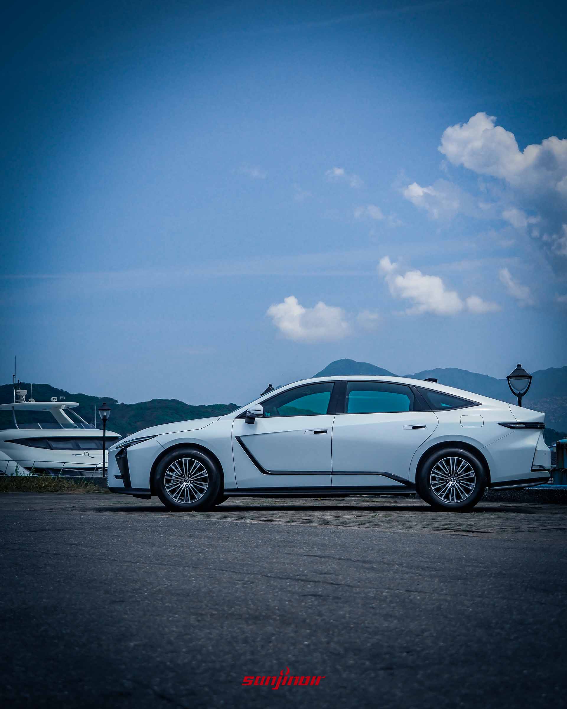 白色Lexus ES 300h的車側全景,展現修長的車身比例與流暢的車頂線條,停放在遊艇碼頭旁。