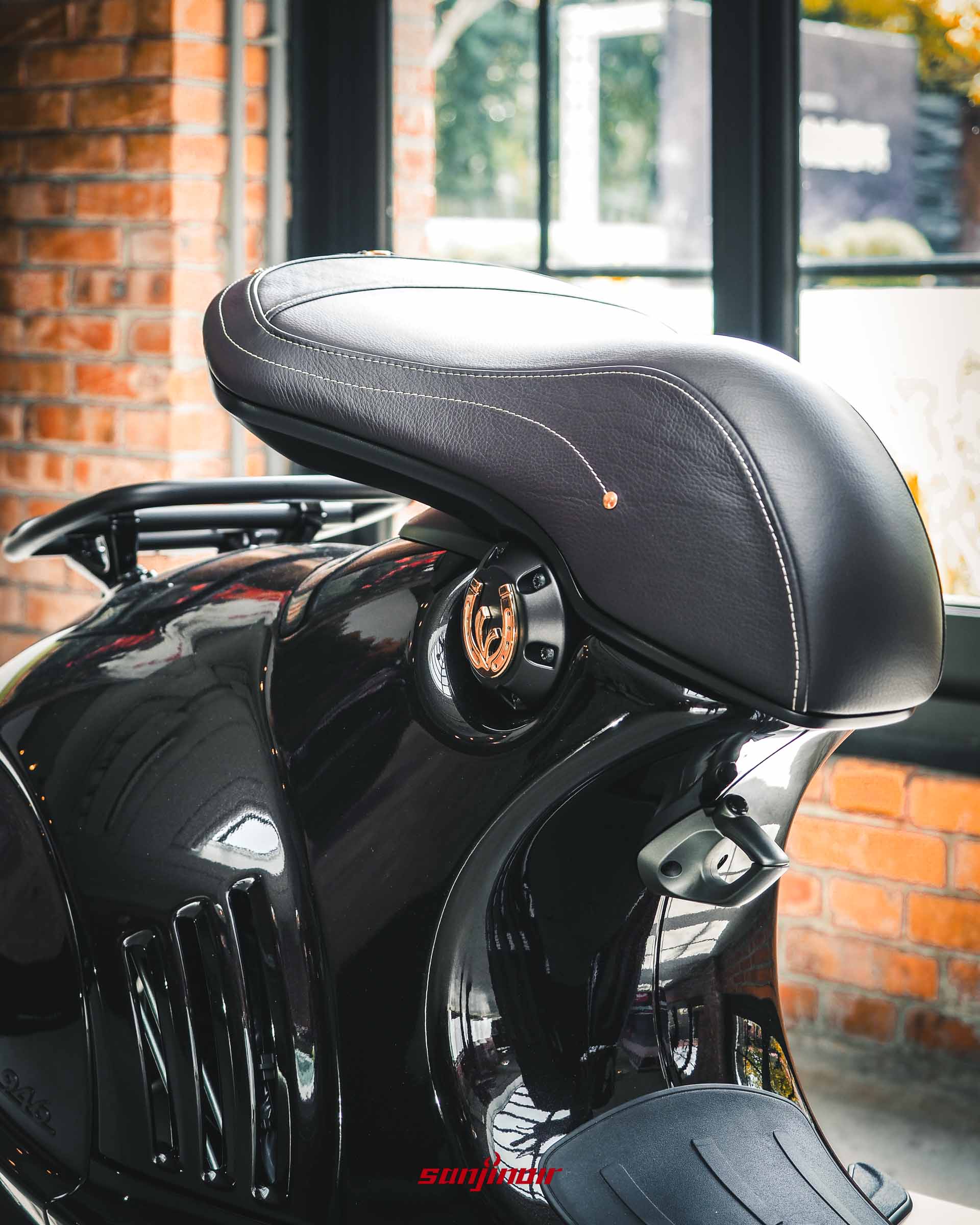 Vespa 946馬年特仕版摩托車細節特寫，展示座墊下方的V字金色馬蹄鐵圖騰與亮面黑車身質感。