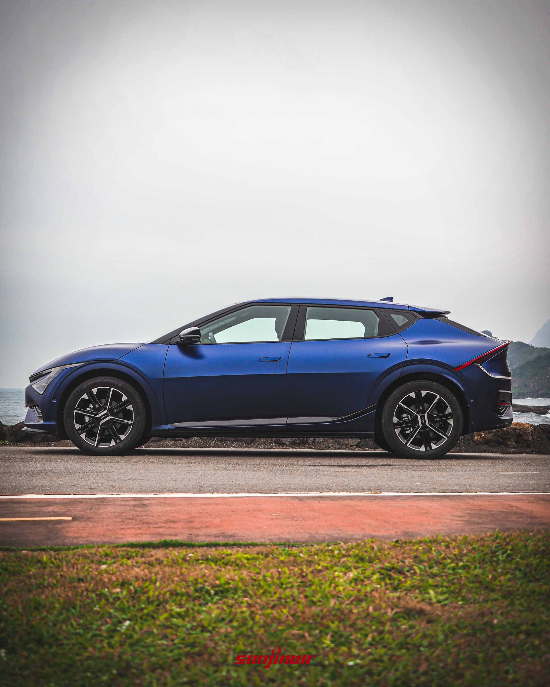 藍色啞光Kia EV6 GT-Line電動車側面照片，停在海邊道路上，展示車身線條和20吋輪圈。