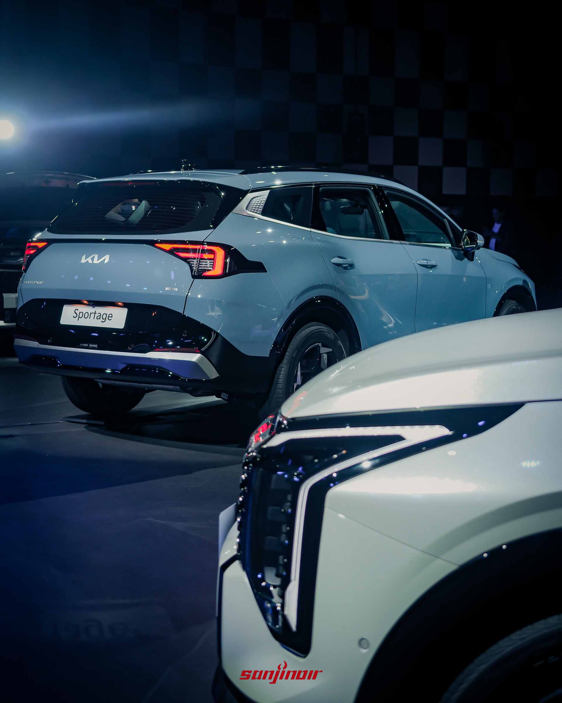 一台晨霧藍Kia Sportage的車側後方視角，展示Star Map LED尾燈、KIA LOGO、車牌上的Sportage字樣，前景有另一台車的日行燈光條。