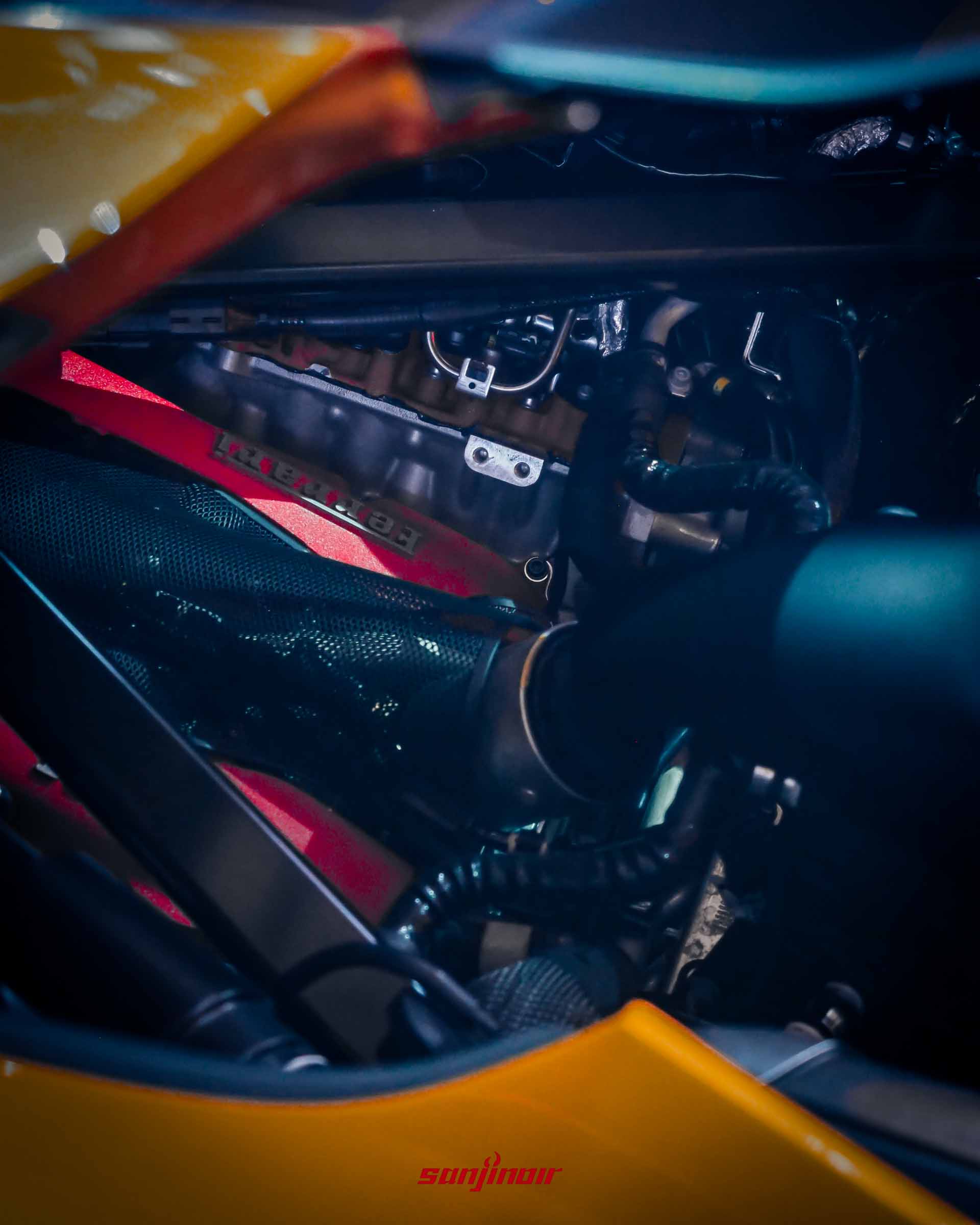 引擎艙內細節。可看見 F154FC V8 引擎的一部分，其上有「Ferrari」字樣的紅色凸輪軸蓋。大量碳纖維結構環繞，銀色金屬製的「Ferrari」銘牌位於照片中央。