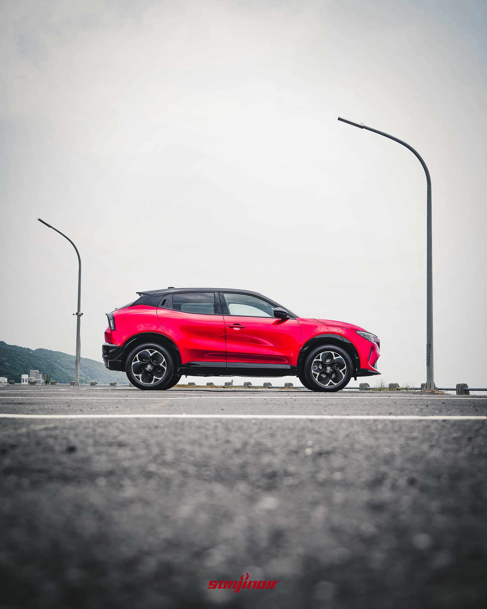 紅色Alfa Romeo Junior車身側面全景,搭配黑色車頂、18吋輪圈,背景為天空與海岸。