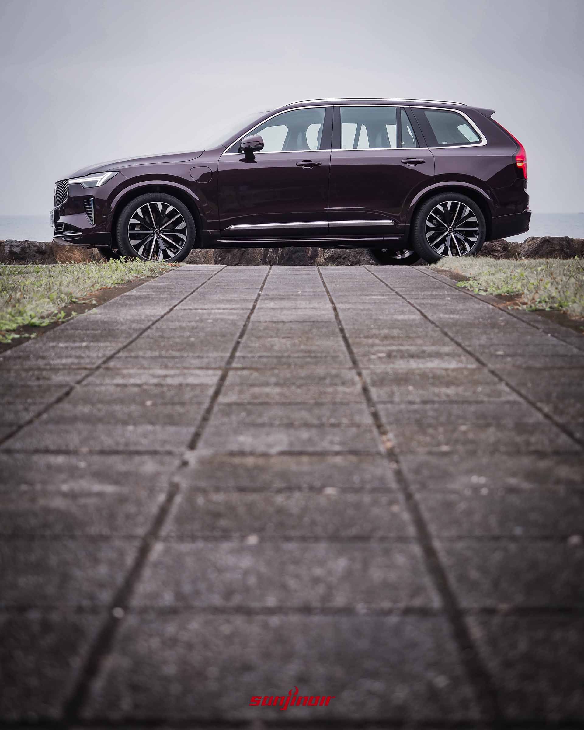 從石磚步道低角度往上拍攝Volvo XC90 T8 Ultra的車身側面全景,展現出宏偉的大型休旅尺碼。