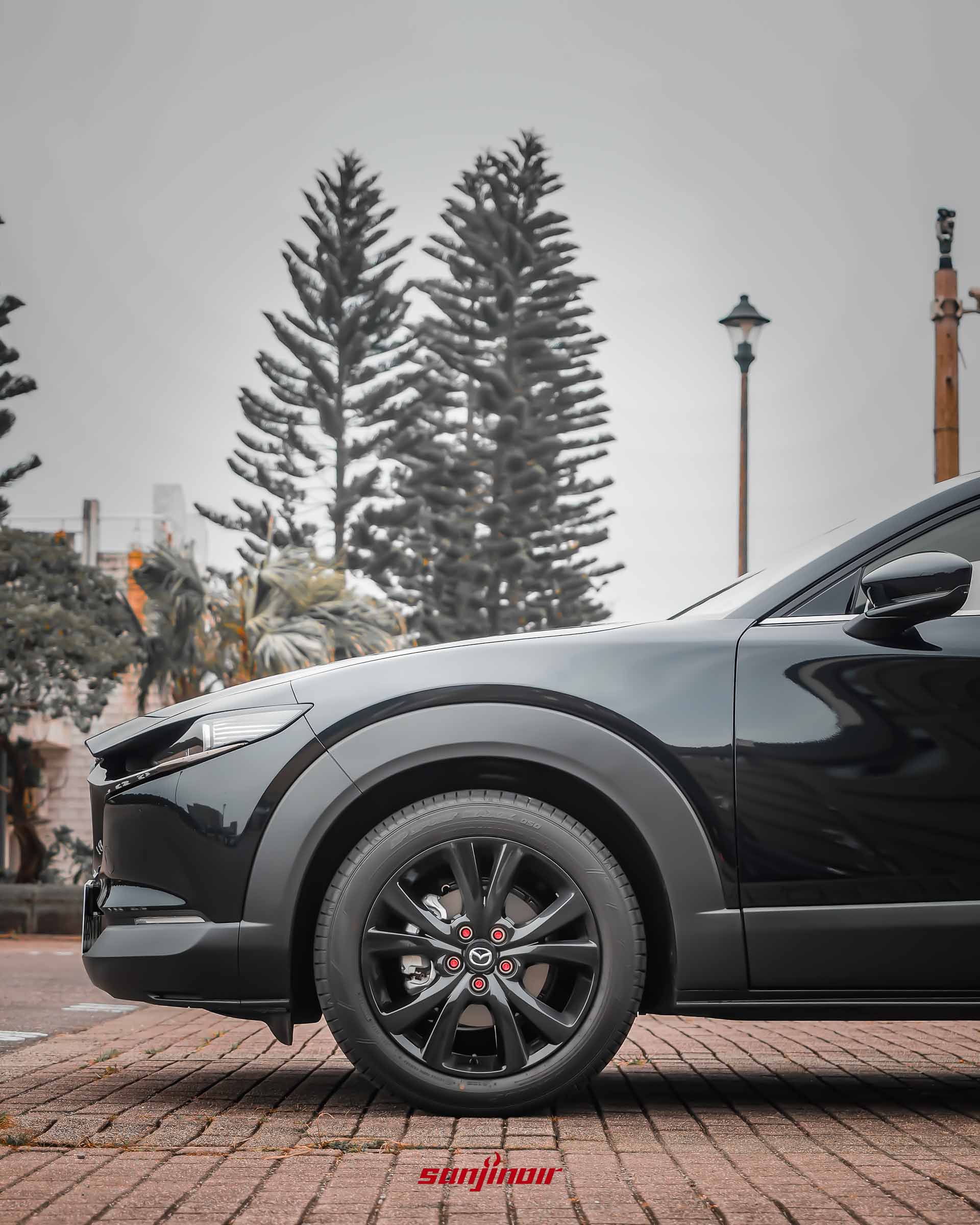 黑色MAZDA CX-30 20S Homura車側前段特寫,展示黑色防刮輪拱與18吋黑色鋁合金輪圈。