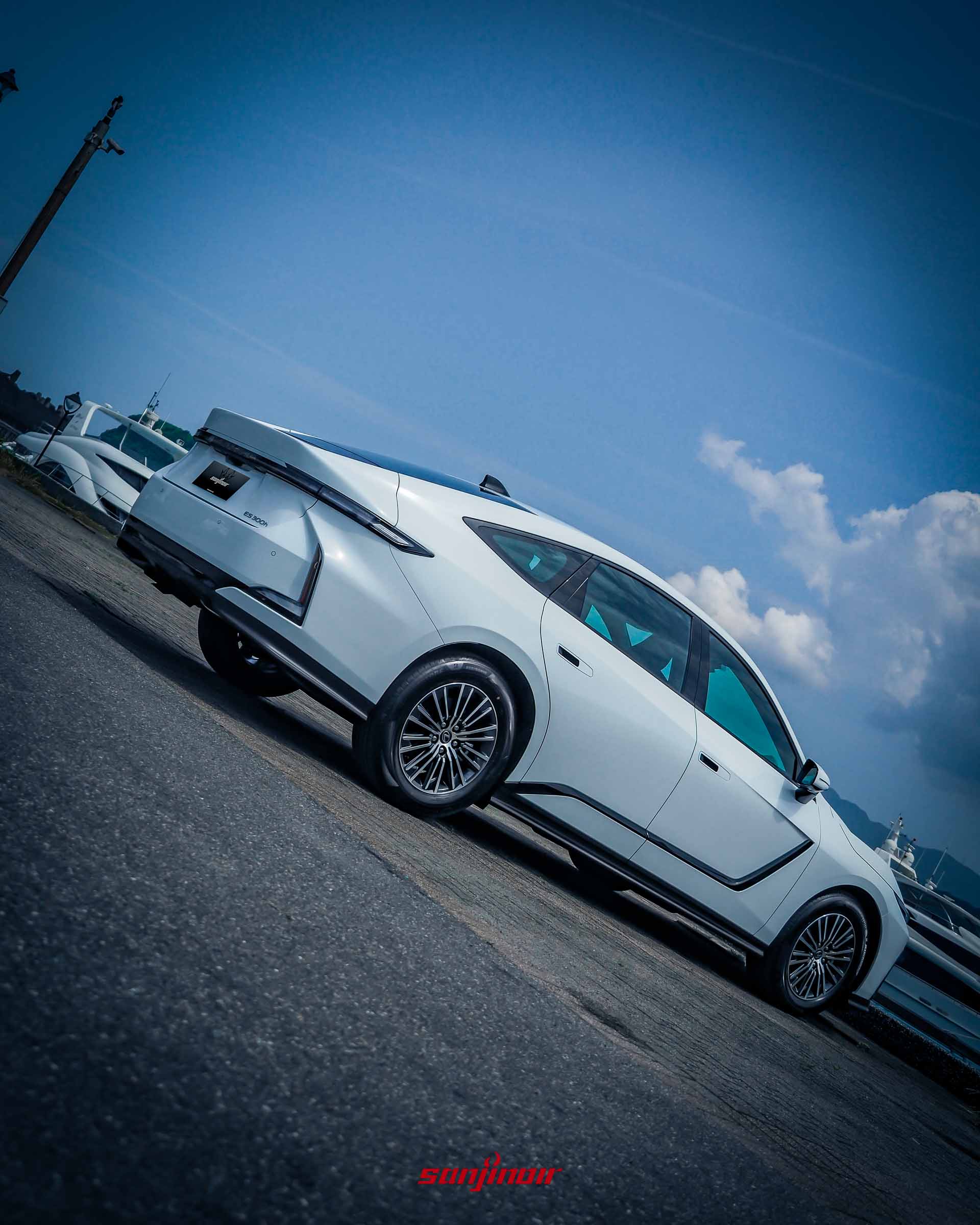 從右後方低角度拍攝的白色Lexus ES 300h,展示貫穿式尾燈設計與乾淨的車尾線條。