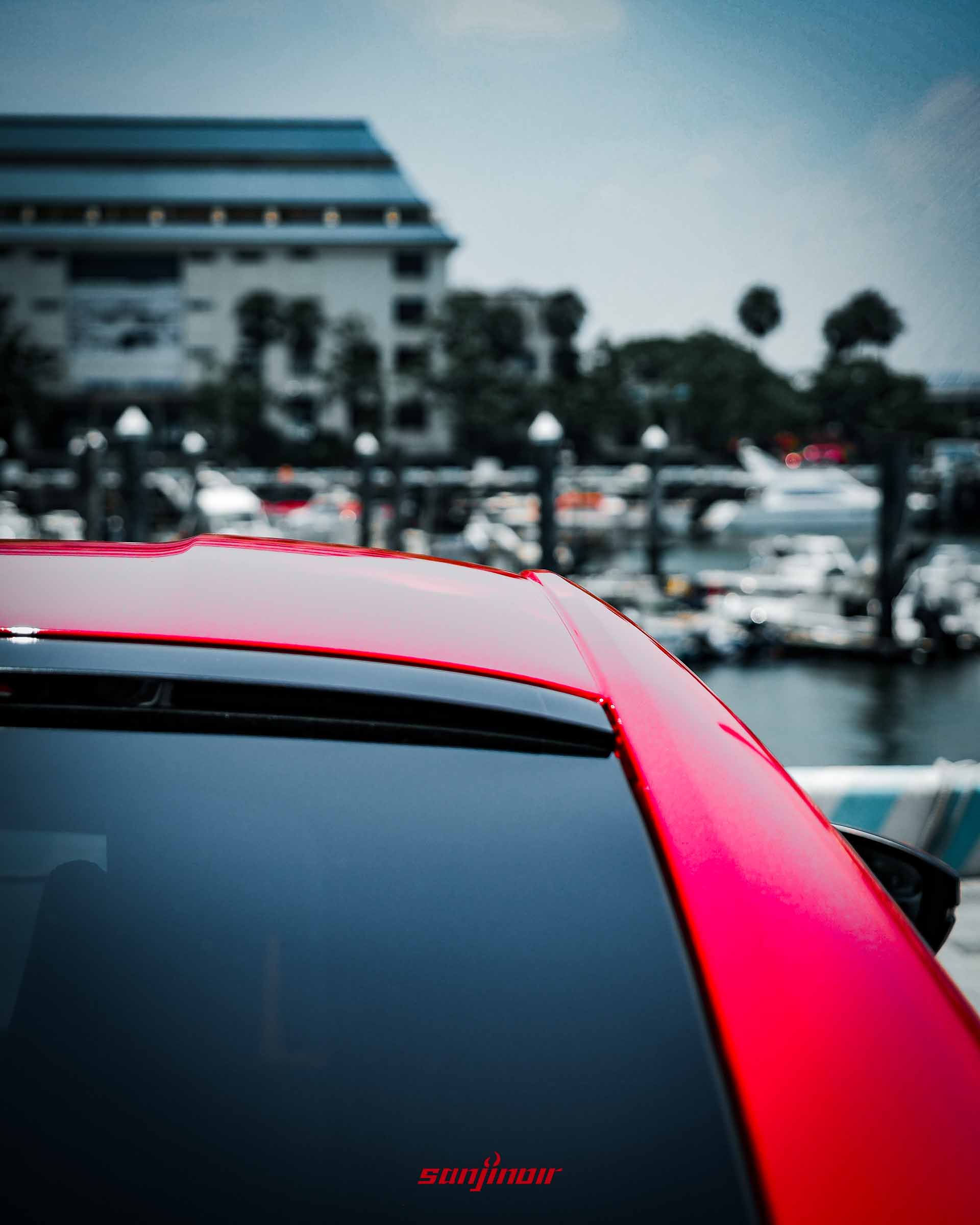 特寫紅色HONDA Prelude的車頂與後擋風玻璃交界處,背景為模糊的港口遊艇。
