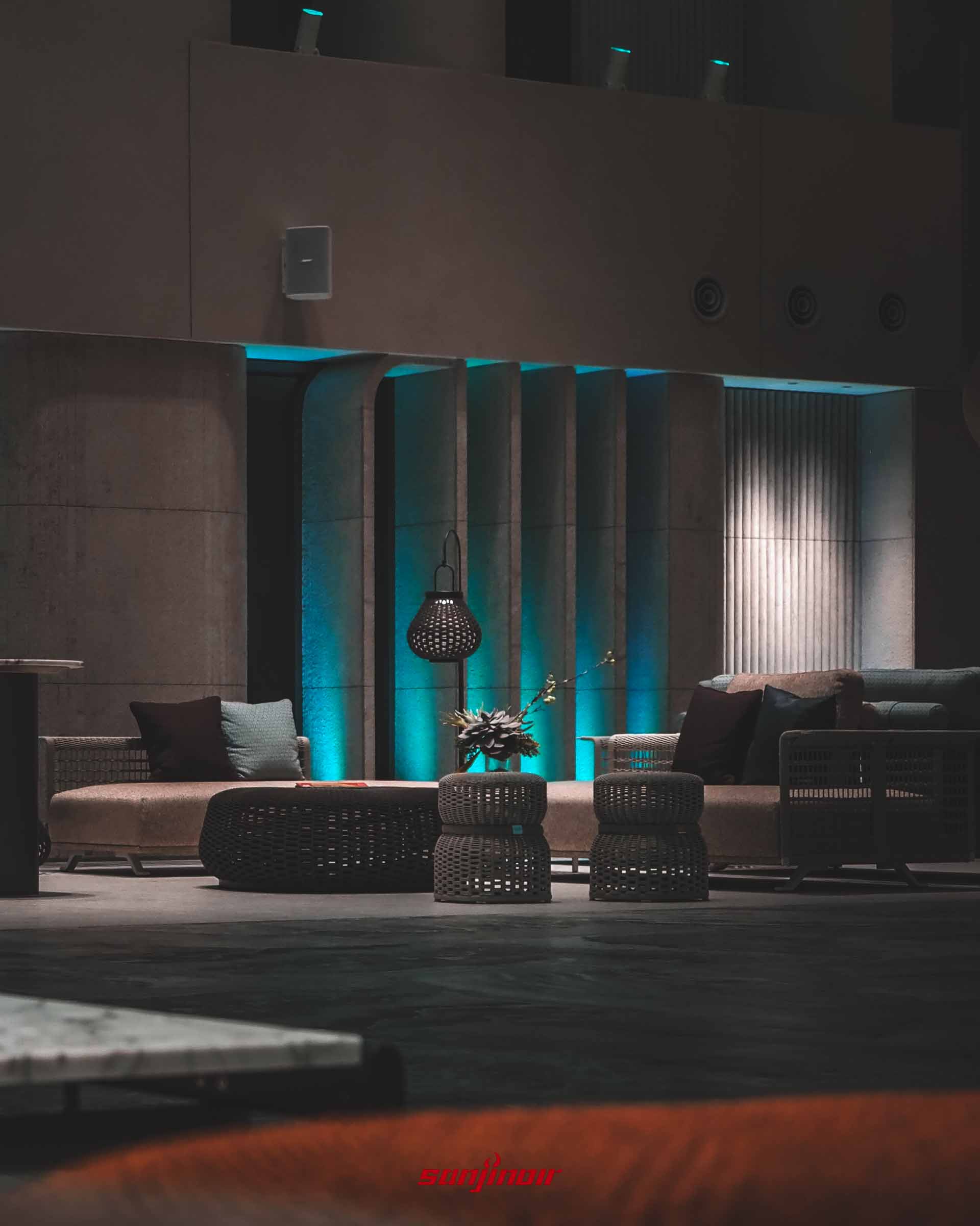 大廳沙發區近景,設有米白色沙發、編織圓凳與造型地燈。