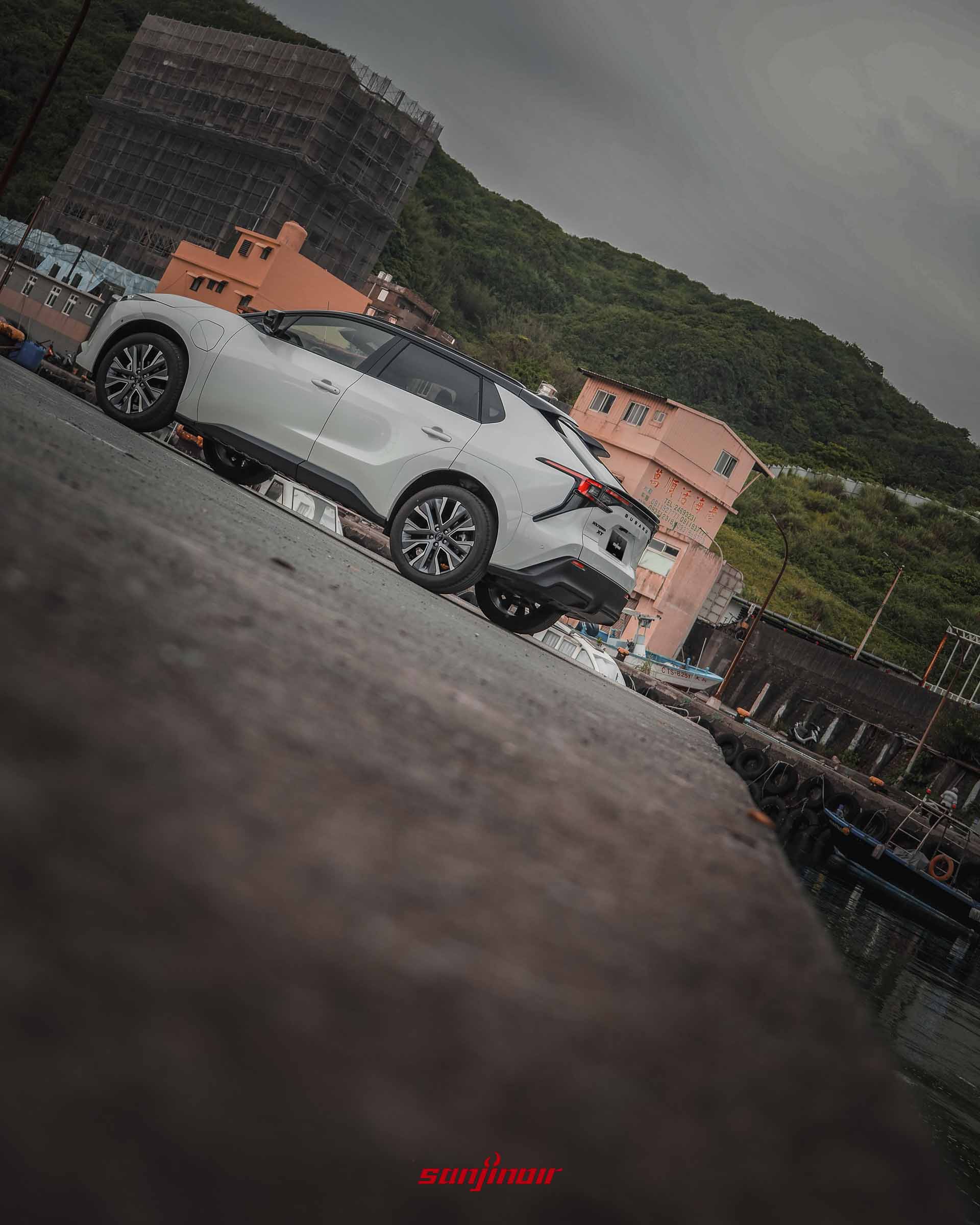 白色Subaru Solterra XT停放於漁港旁，展示車尾擾流板與貫穿式尾燈設計。