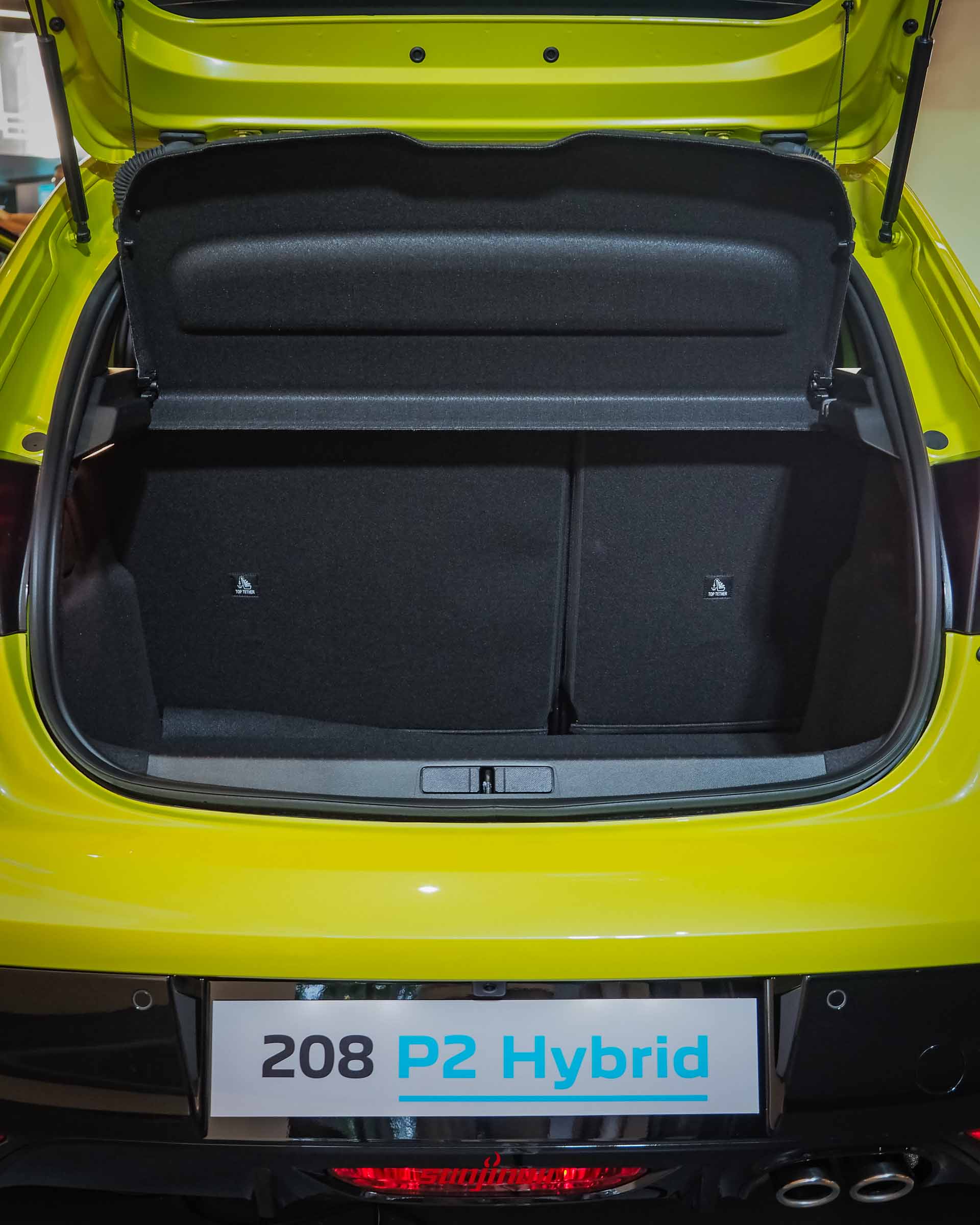PEUGEOT 208 P2 Hybrid開啟後行李廂門的正面照片,展示內部平整的置物空間與後座椅背上的兒童安全座椅固定扣。