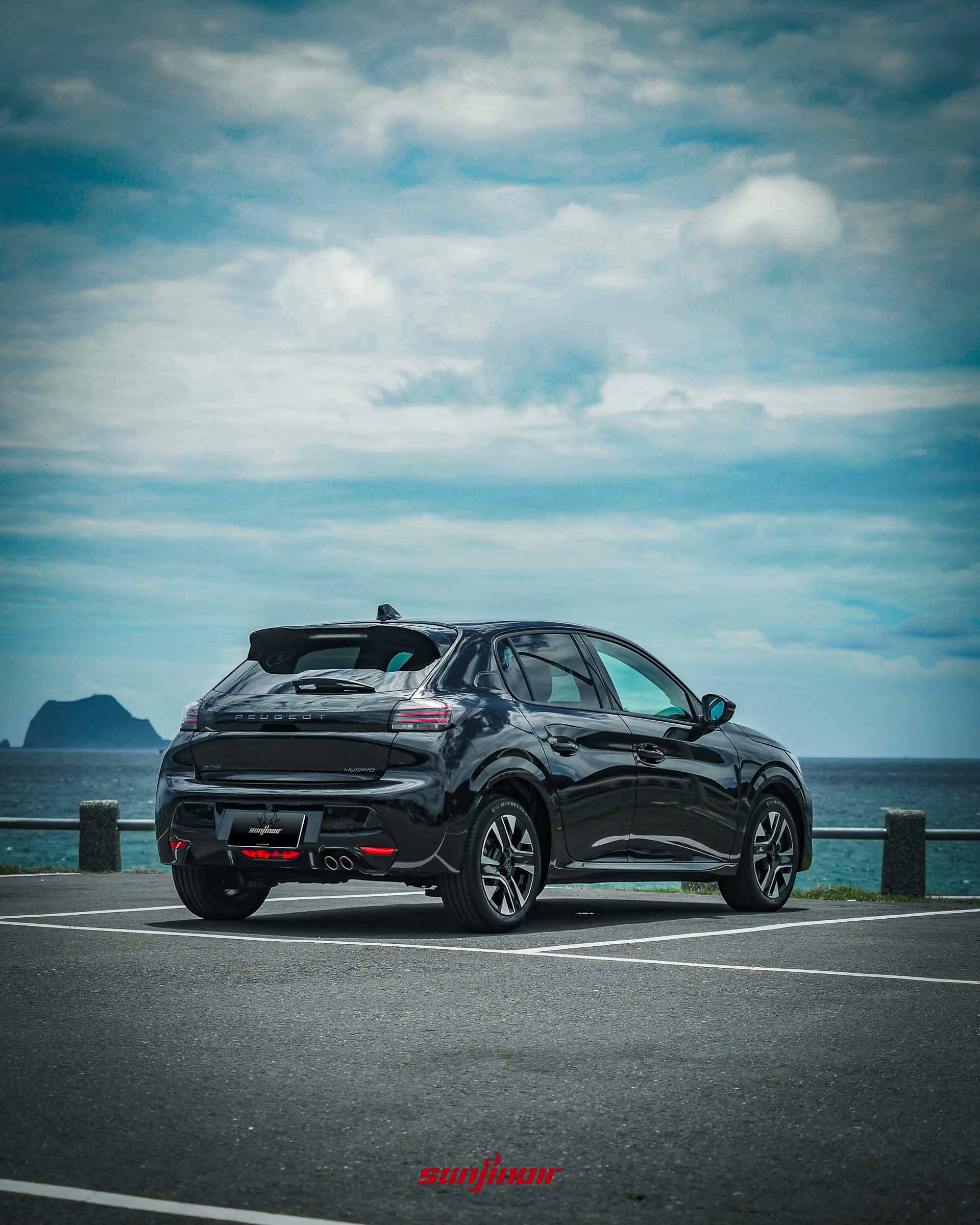 黑色PEUGEOT 208 Hybrid右後方側視角停放於臨海停車場。