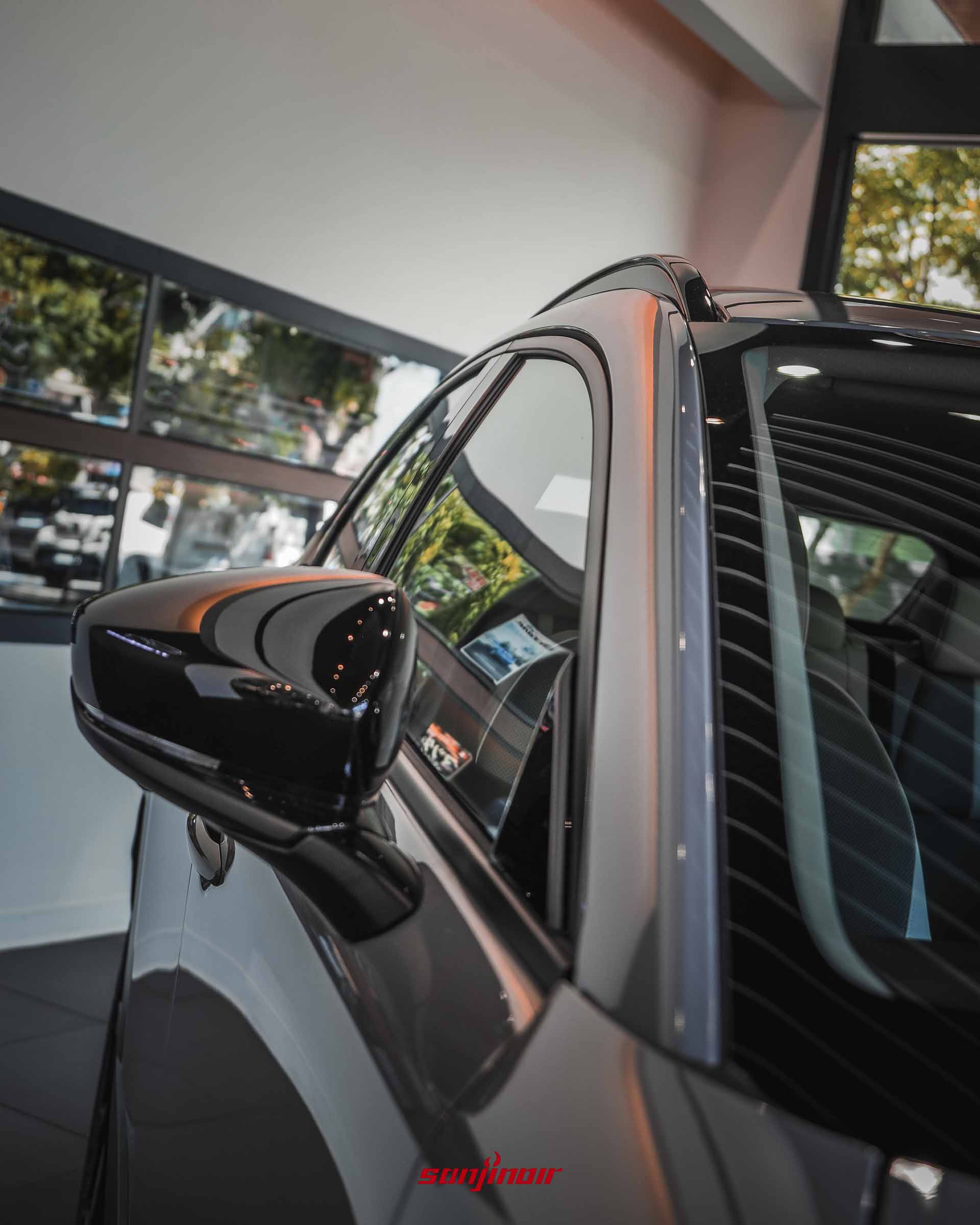 近距離特寫MAZDA CX-30 Air Edition的黑化後視鏡外蓋、黑化窗框飾條與黑化車頂架,表面反映出周遭光影。