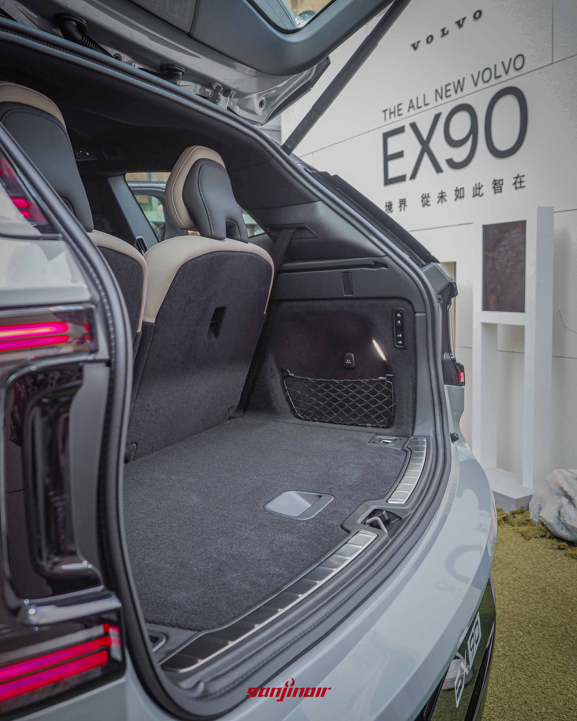 Volvo EX90開啟後車廂的畫面,展示內部深邃且平整的黑色置物空間,右側配有置物網,車廂外背景可見發表會背板。